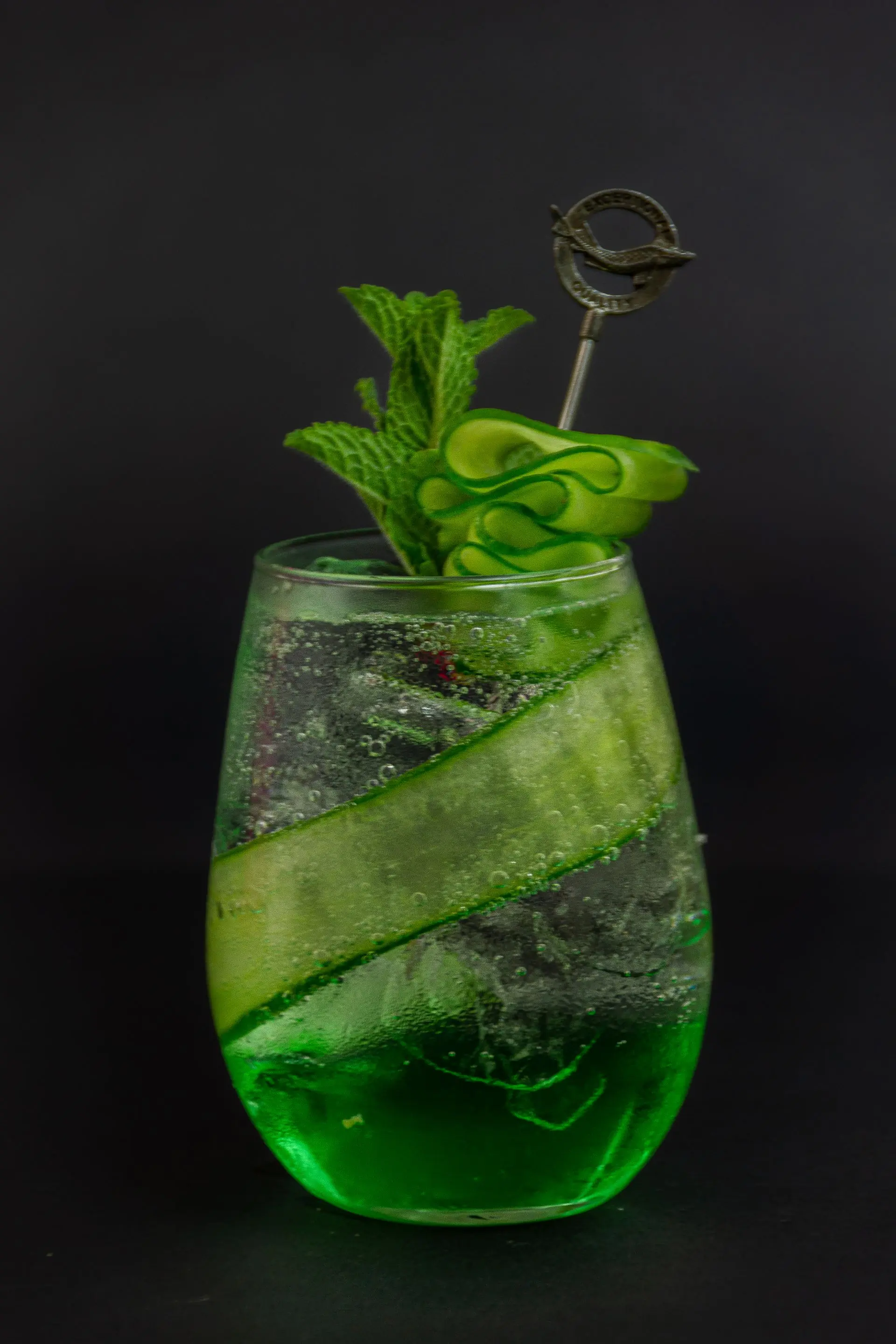 A green cooler with cucumber and mint in a clear glass