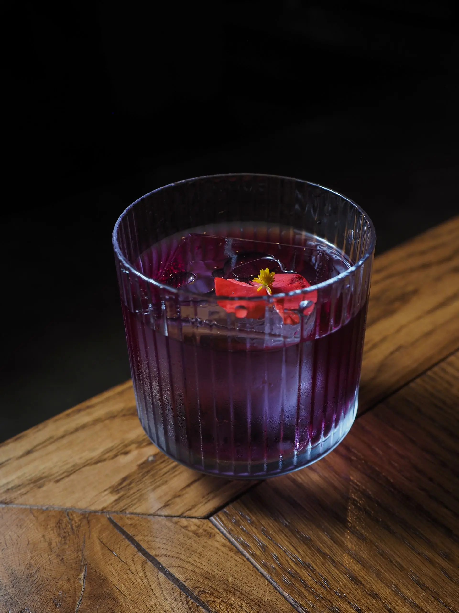 A purple punch in a glass with fruit on the rim