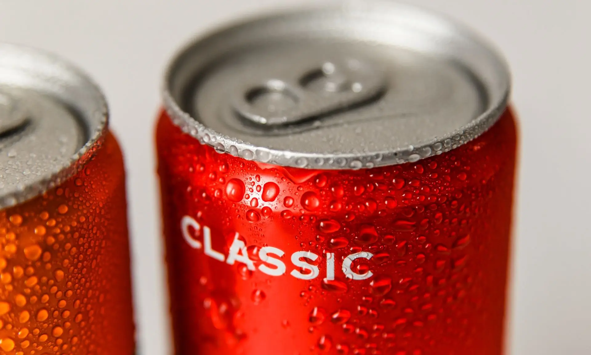 A wet red can of cola shot close, droplets standing on the metal