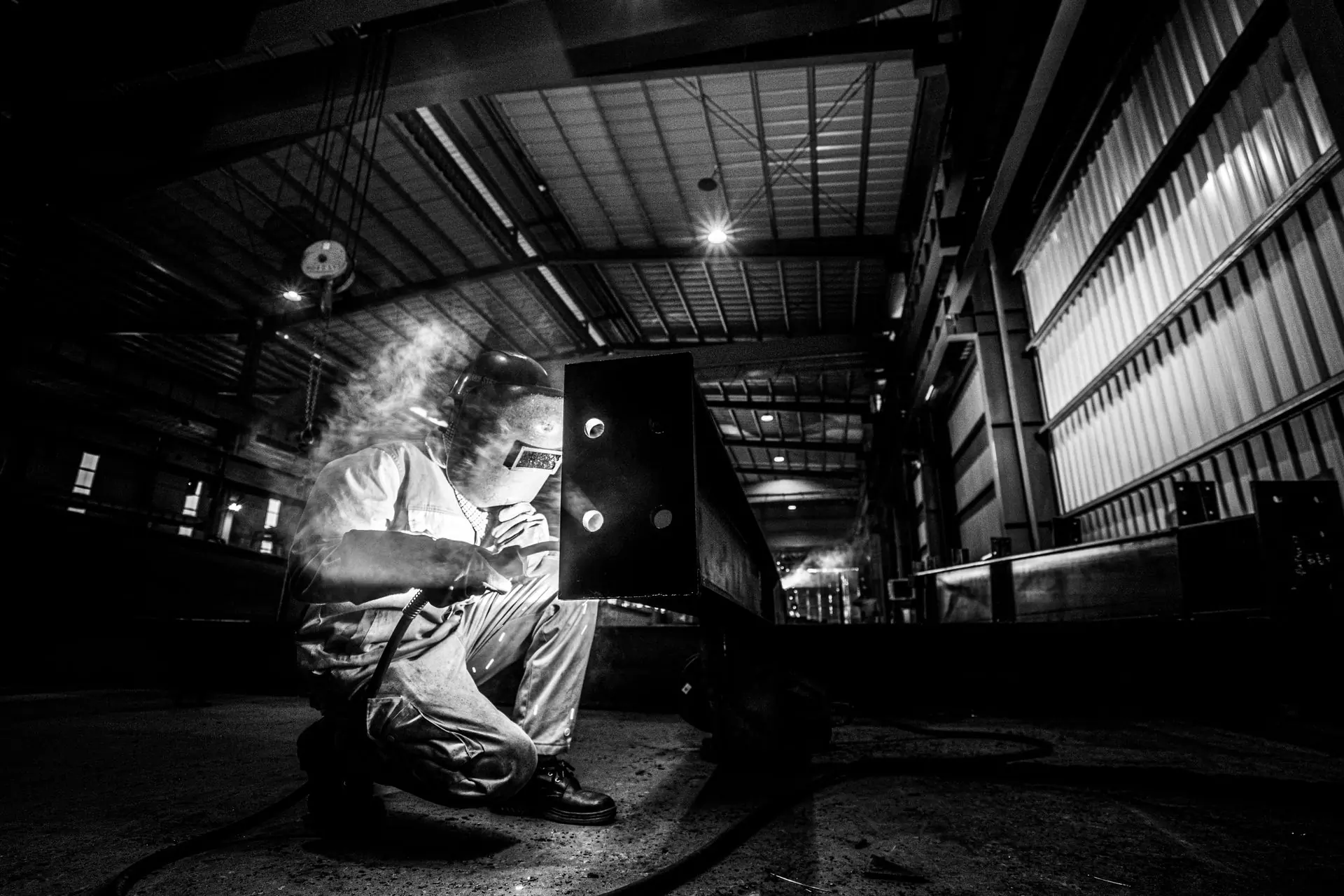 A fabricator at work in an unlit workshop