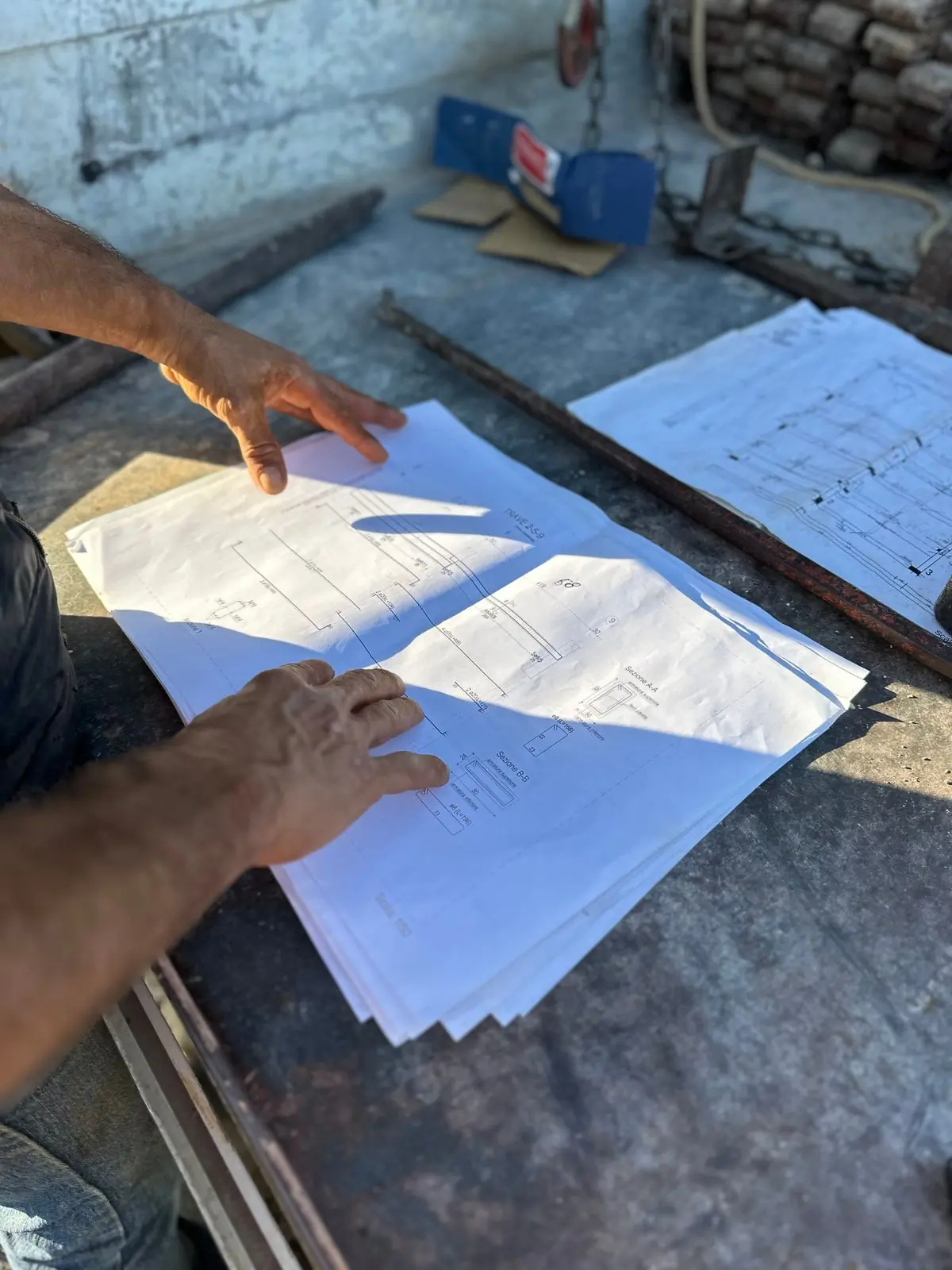 Hands going through a set of drawings on a site table