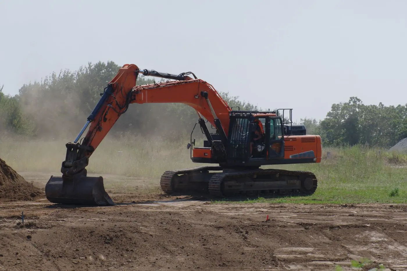 An excavator levelling a cleared plot on a bright morning