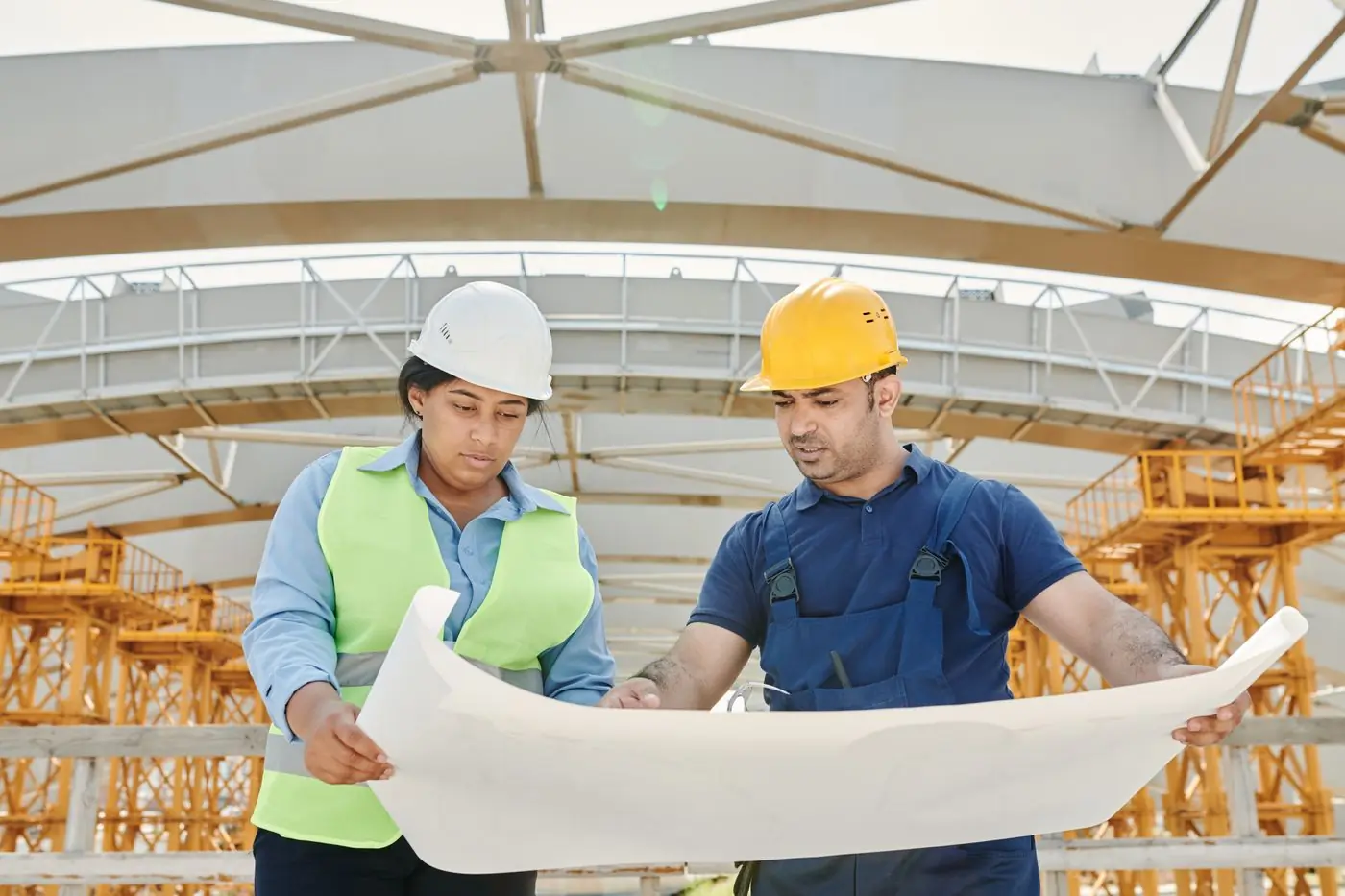 Two engineers going through a drawing under a half-finished roof