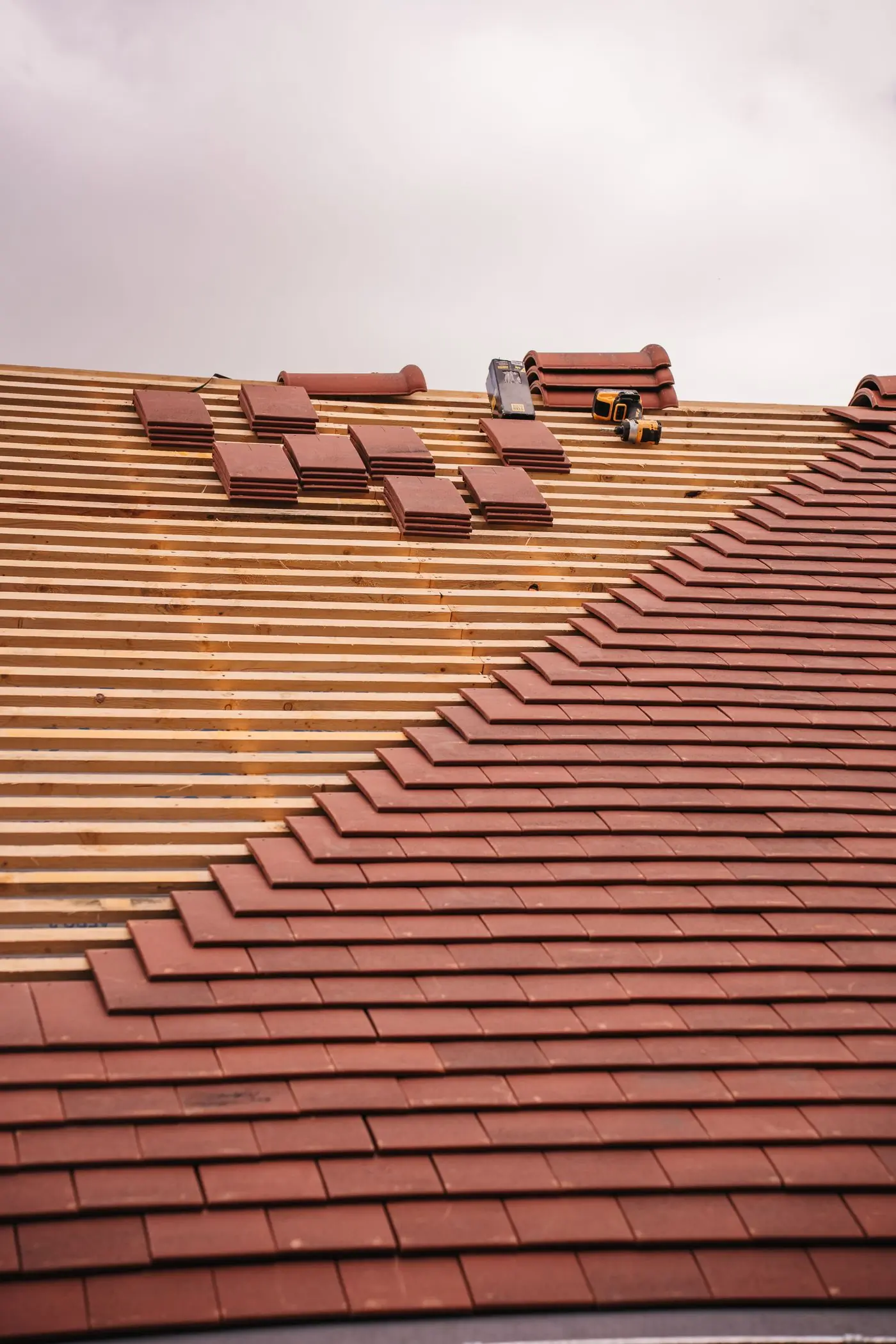 Clay tiles being laid course by course over new battens