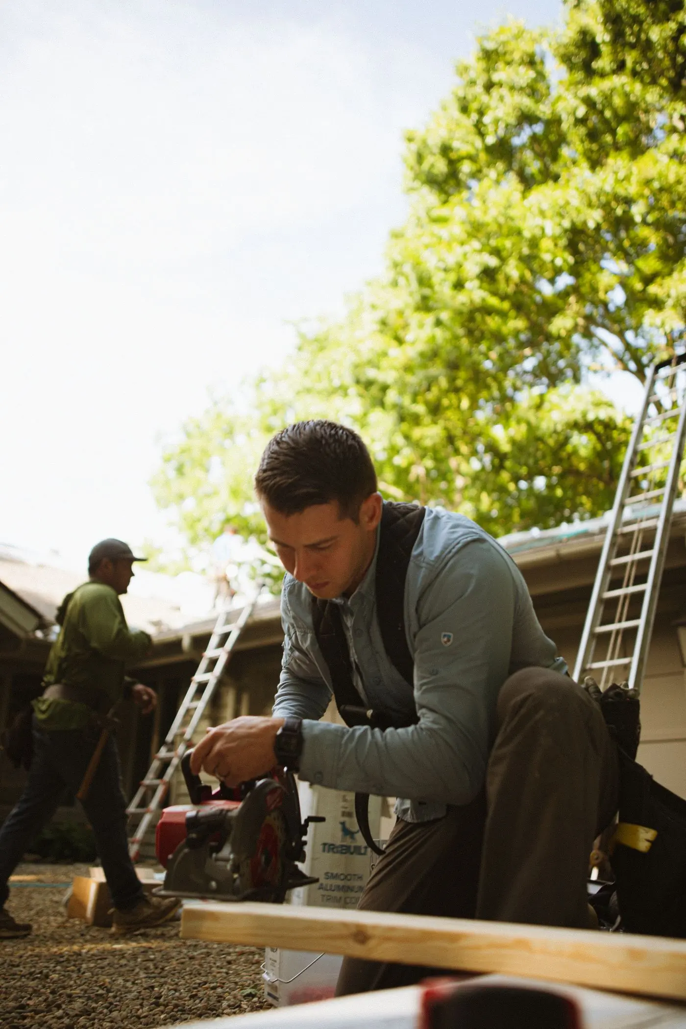 A fitter working at a gutter line with ladders set behind him
