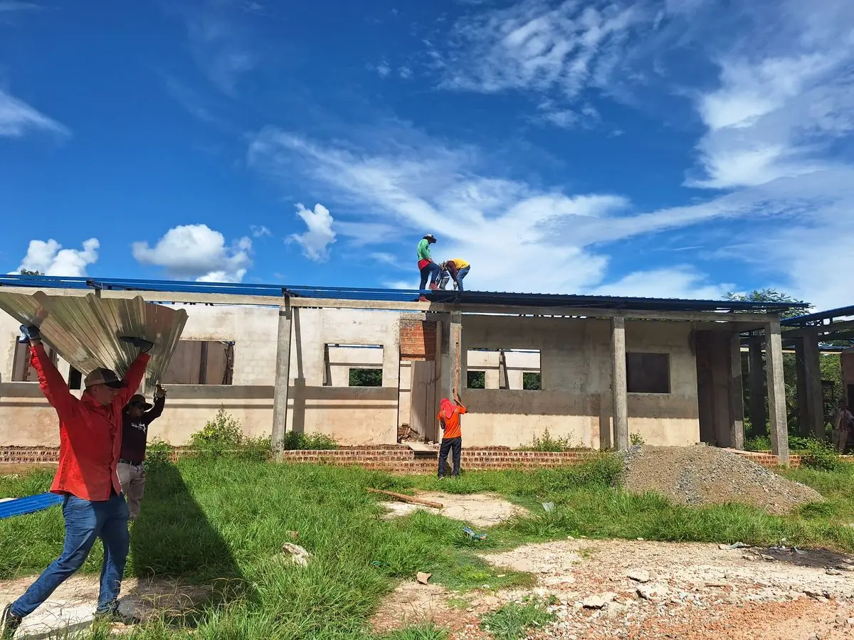 Roofers sheeting an unfinished building against a bright sky