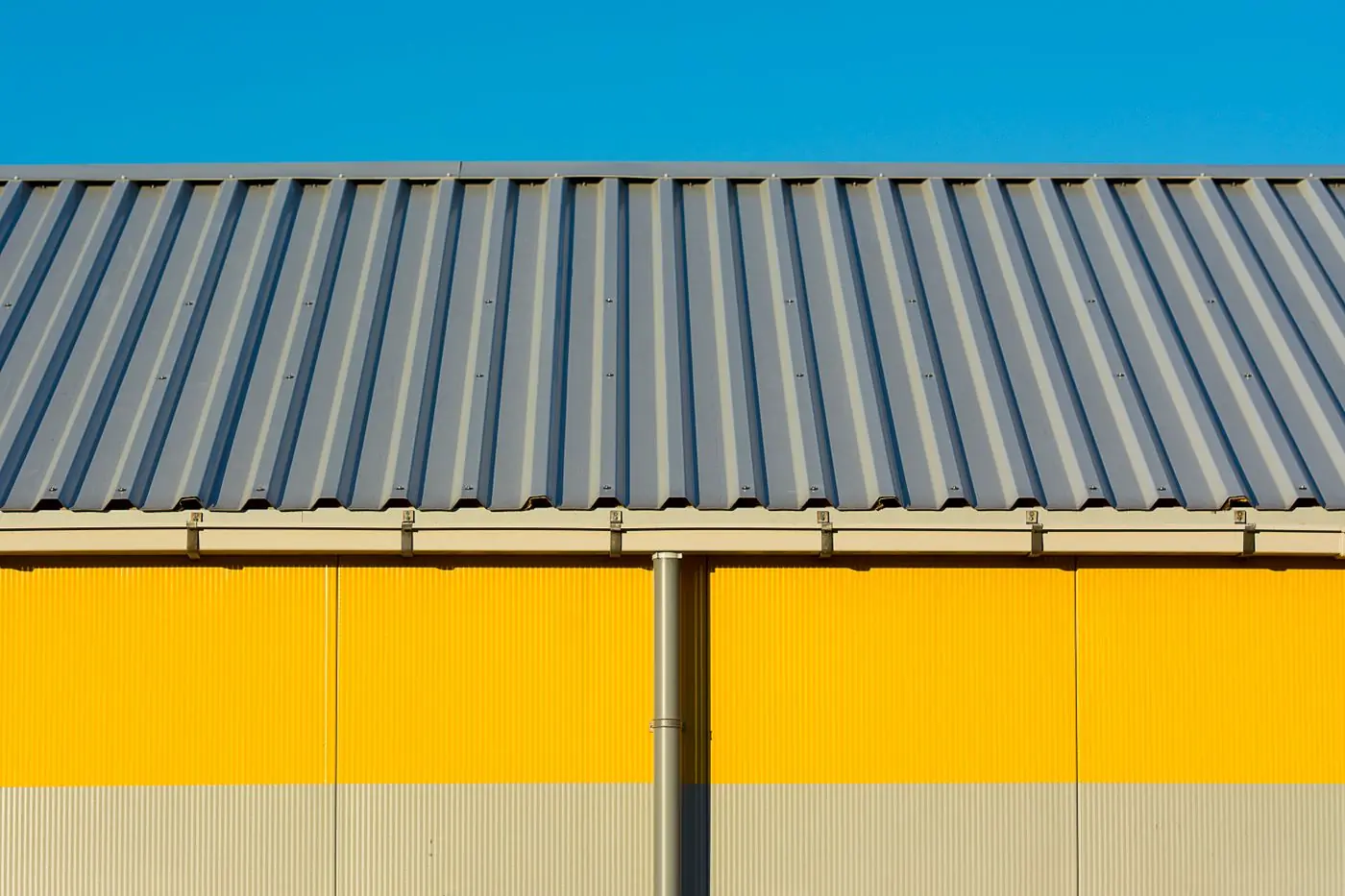 A yellow commercial building under a long corrugated metal roof