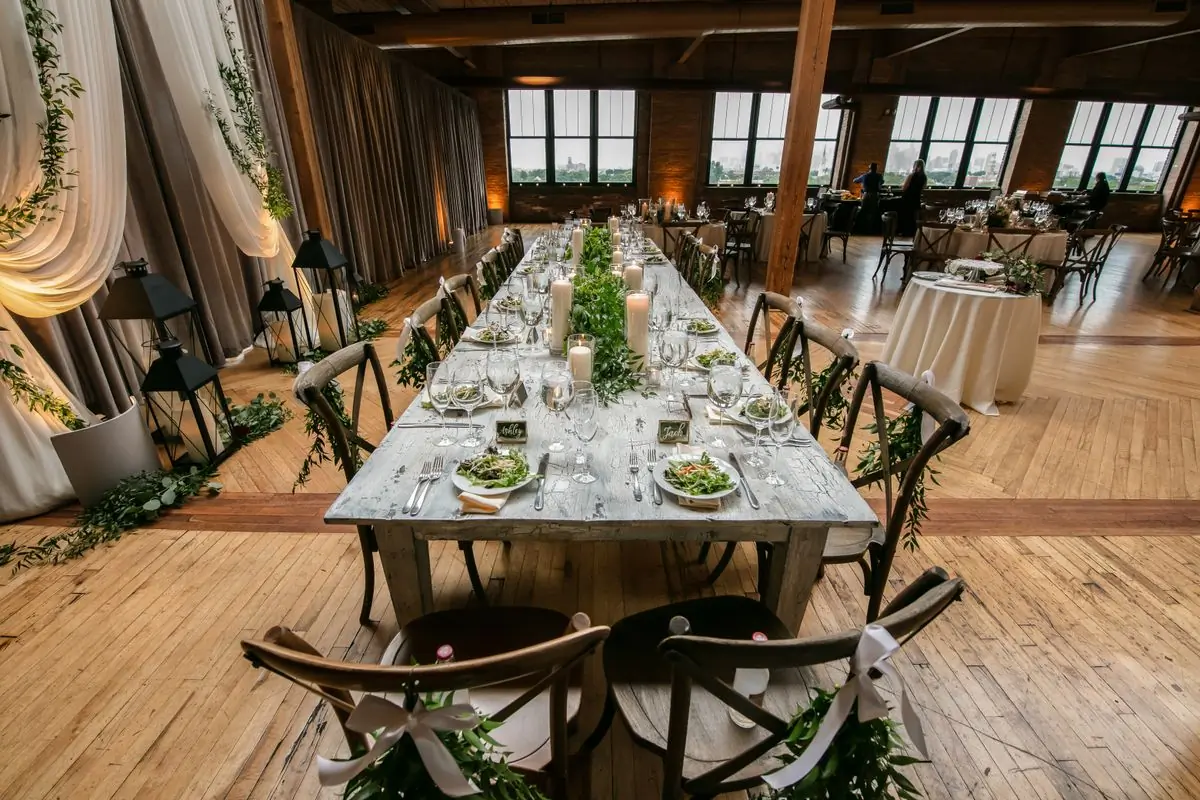 A long reception table dressed with greenery and candles
