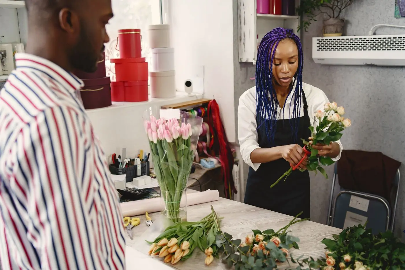 Two florists working over an arrangement on a studio bench