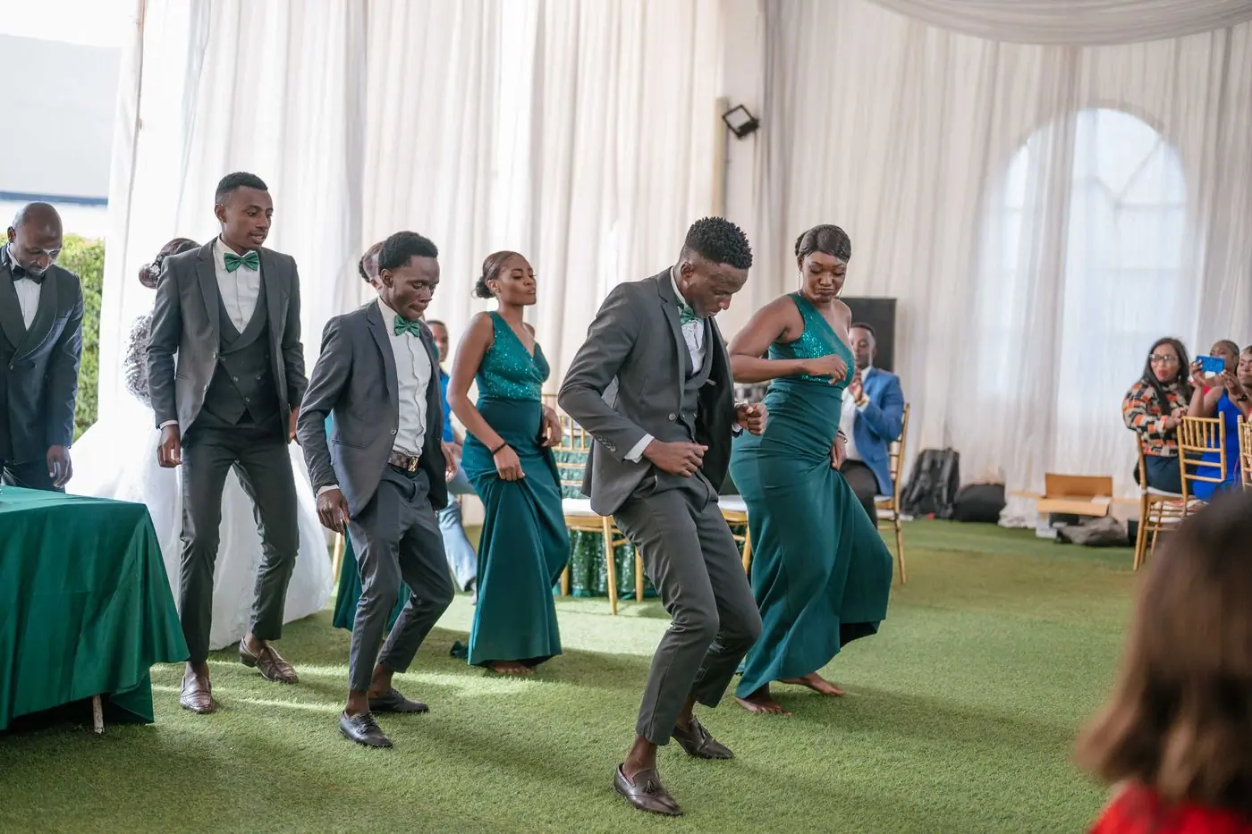 Guests in formal dress dancing together on a lawn under a marquee