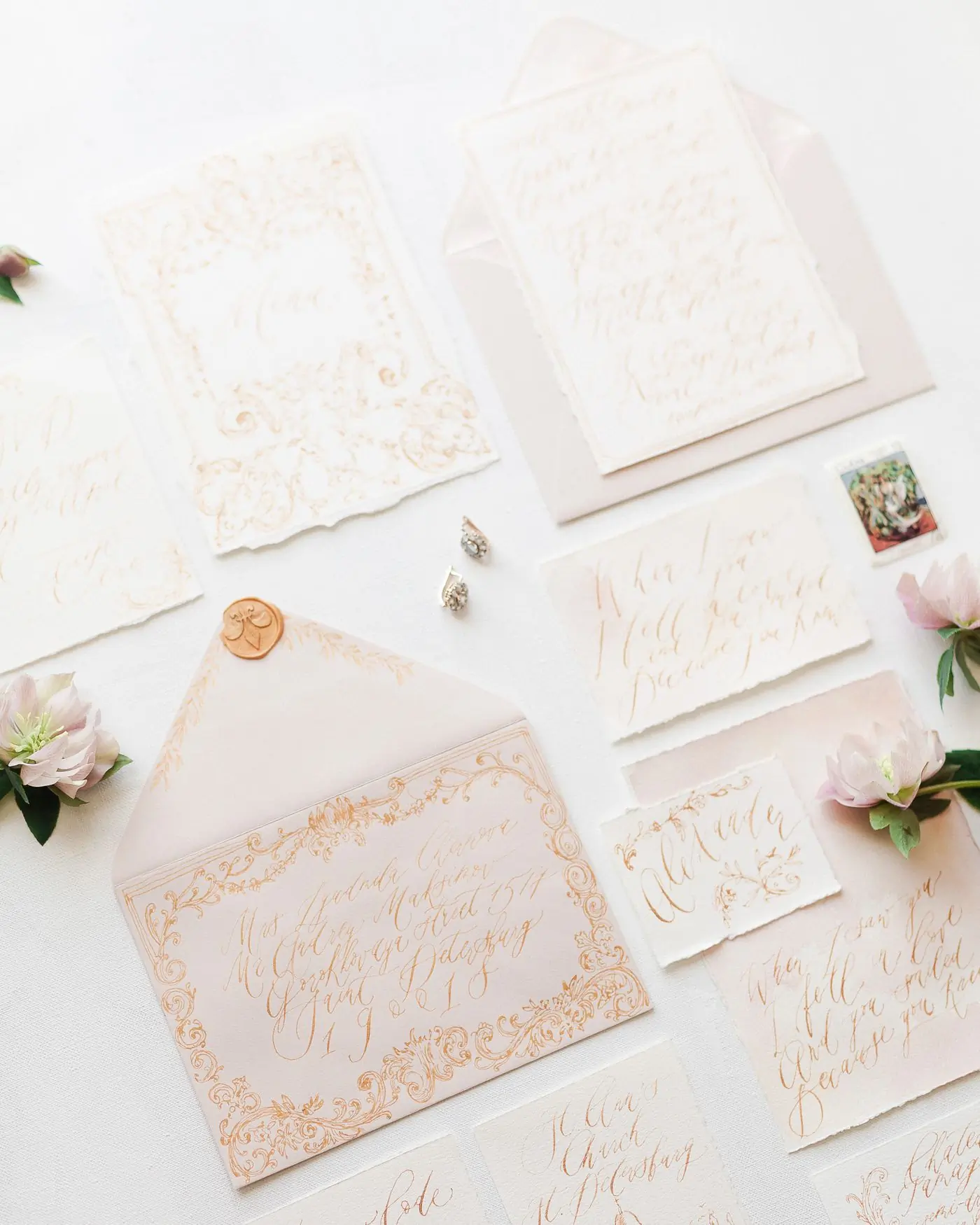 An invitation suite laid out on a pale surface with envelopes and printed cards