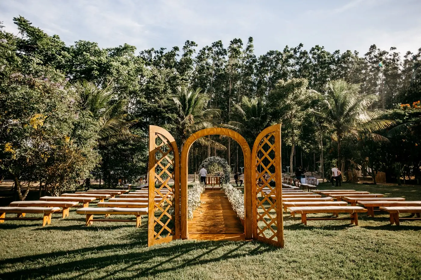 A wooden arbour and rows of benches in a green park