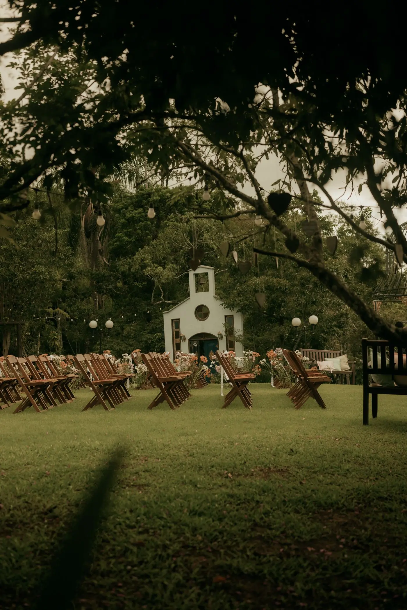 A small chapel beside a lawn set with wooden chairs