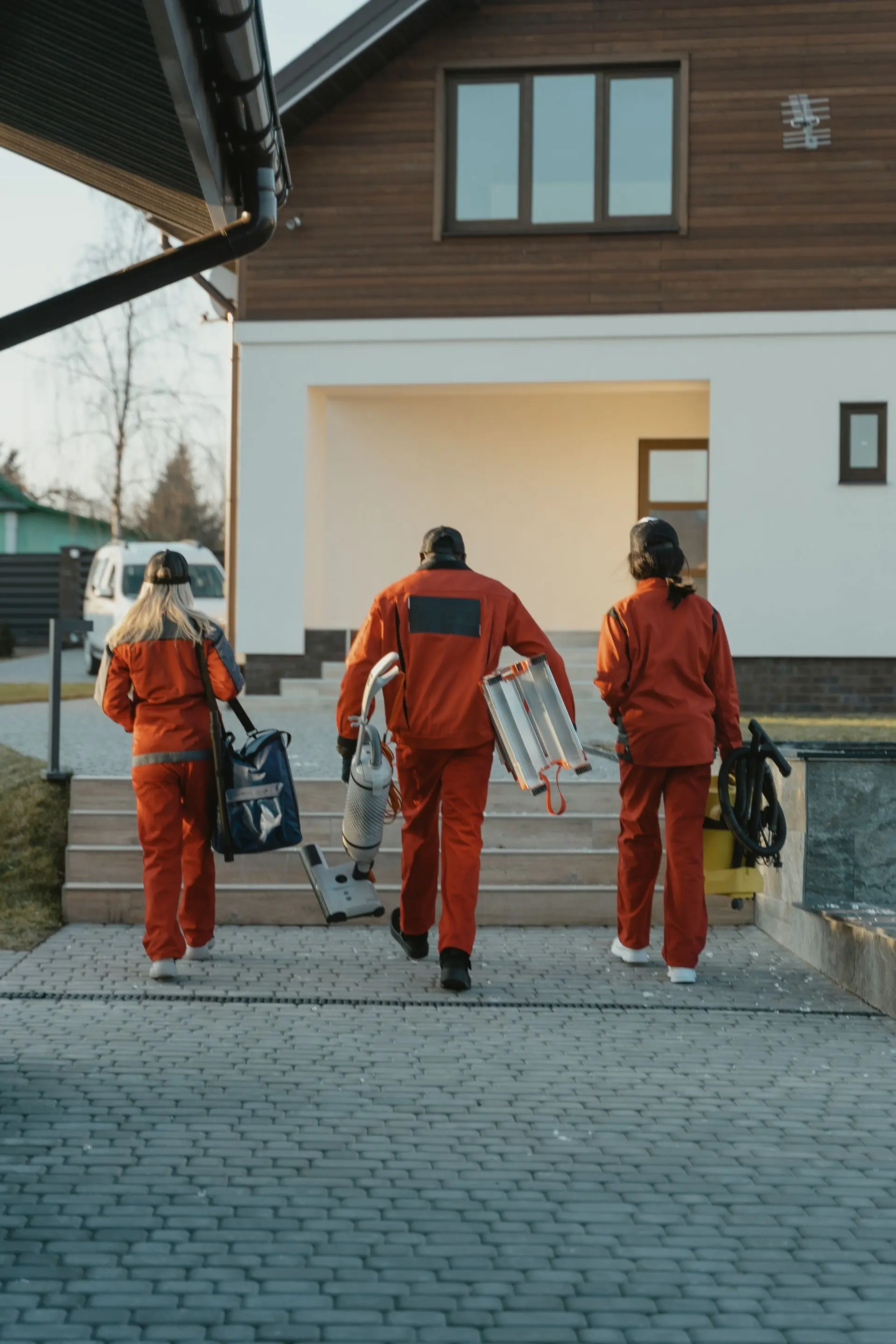 A cleaning team walking up to a house with their equipment