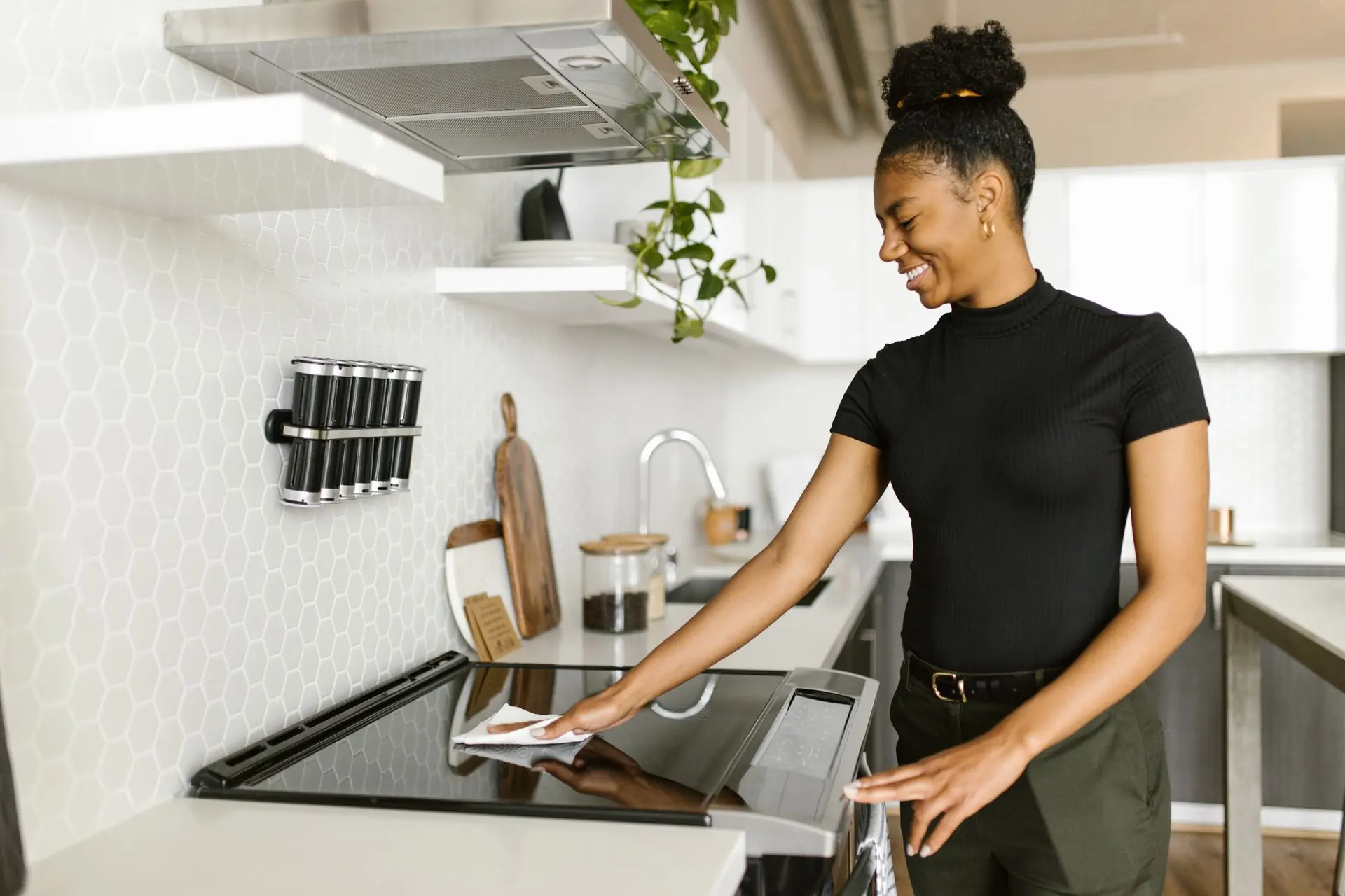 A cleaner wiping down a hob in a bright Accra kitchen