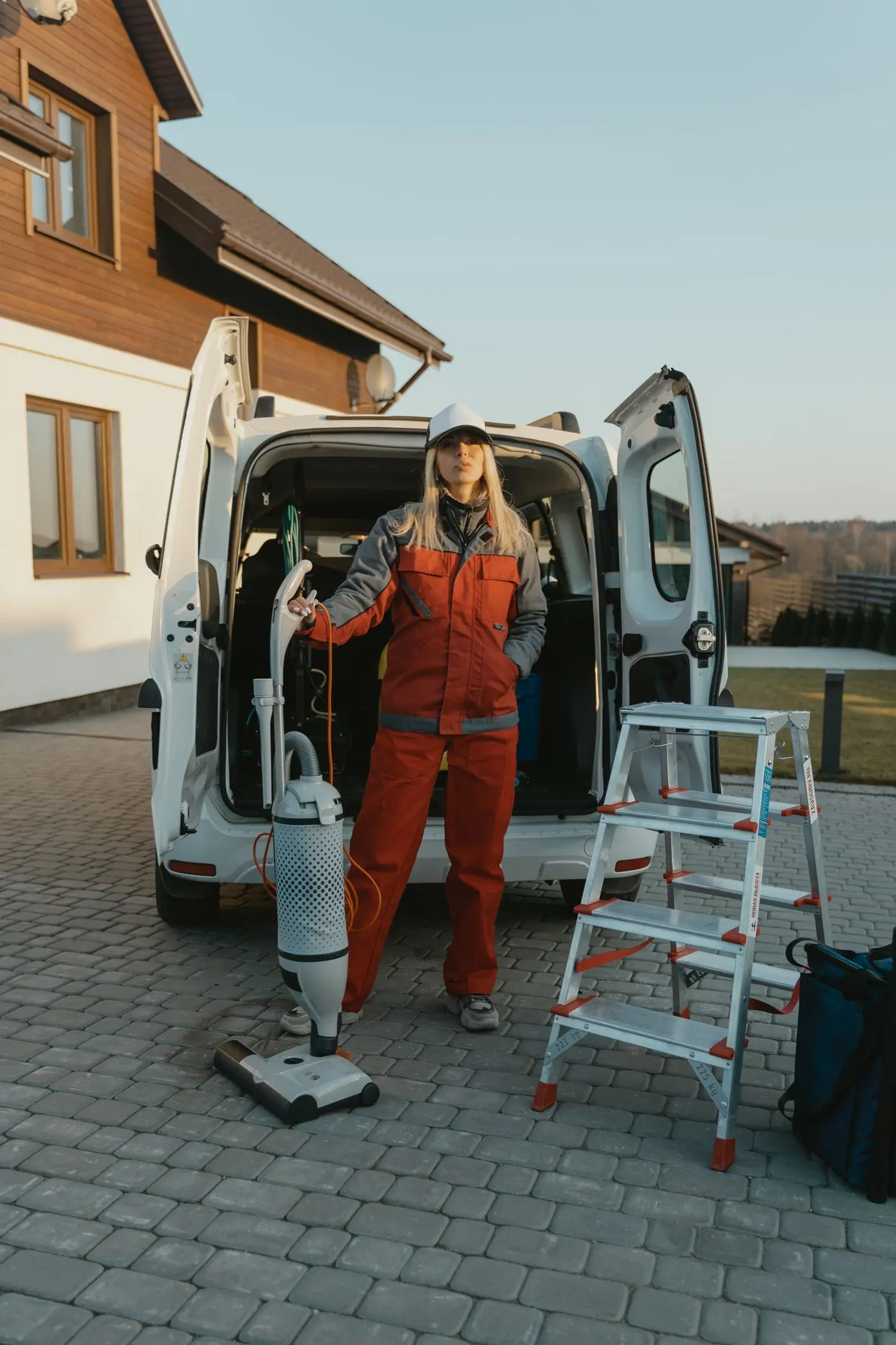 A cleaner unloading equipment from the company van outside a house