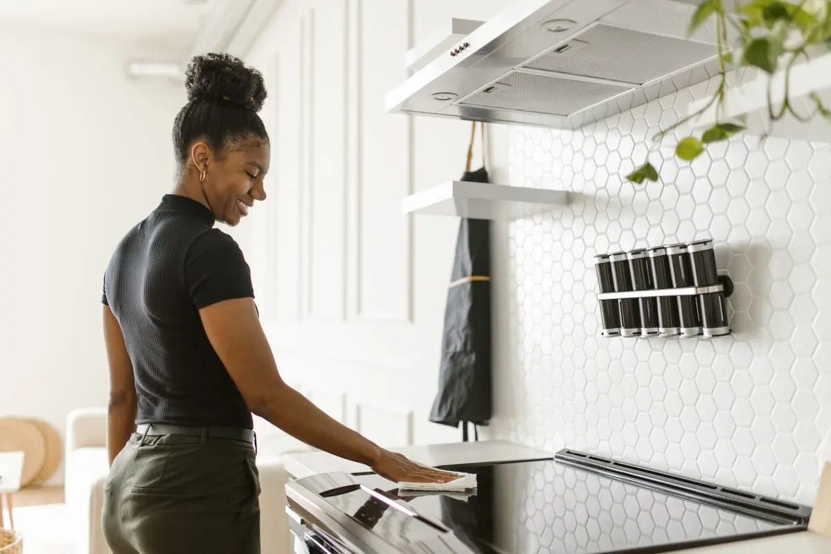 A cleaner wiping down a hob in a bright kitchen