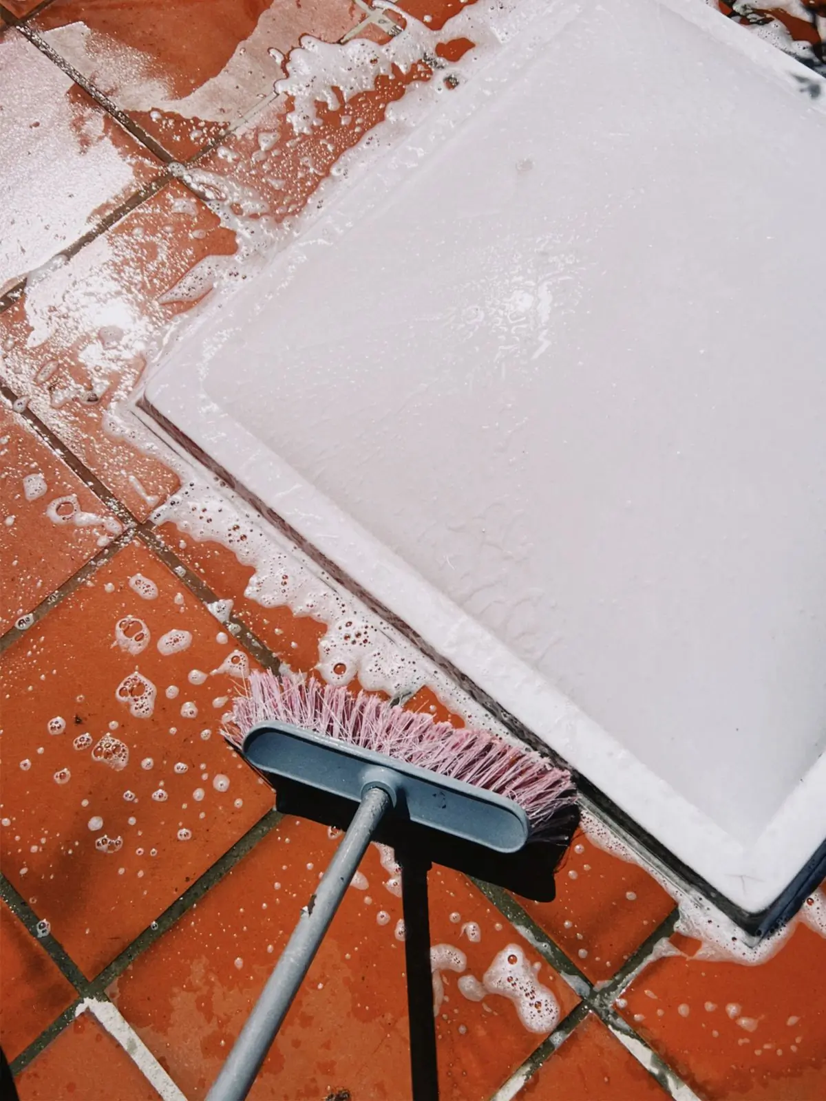 Soapy terracotta floor tiles being scrubbed with a stiff brush