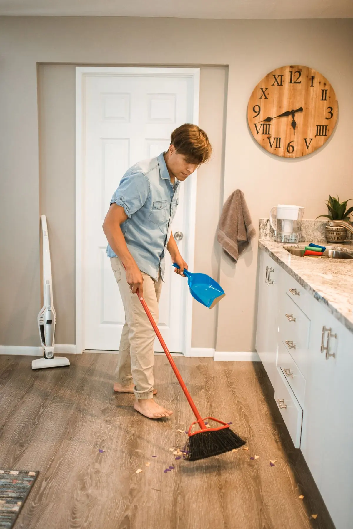 A cleaner sweeping the floor of a bright family kitchen