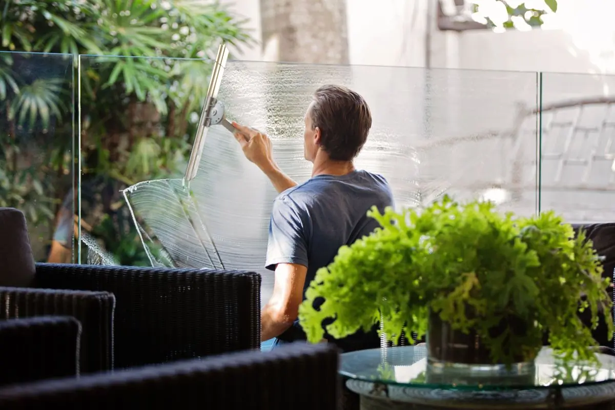 A cleaner working across a full-height glass wall