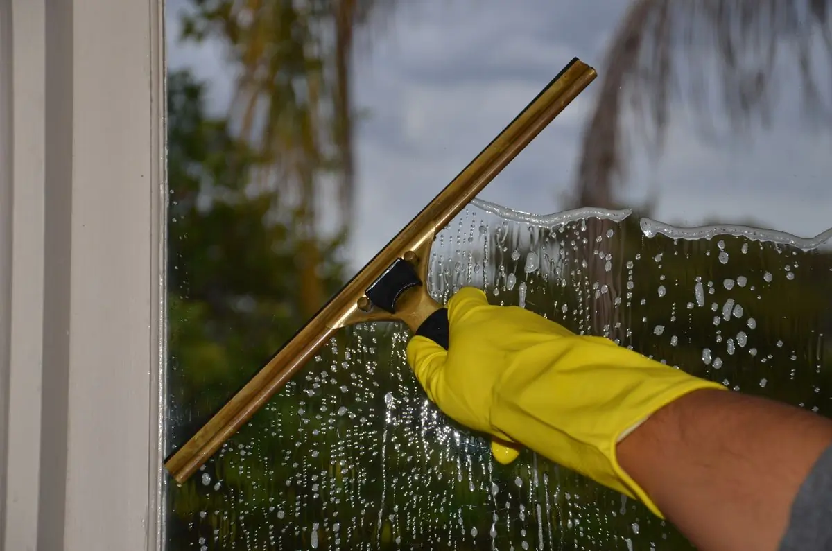 A squeegee pulling water down a soapy window