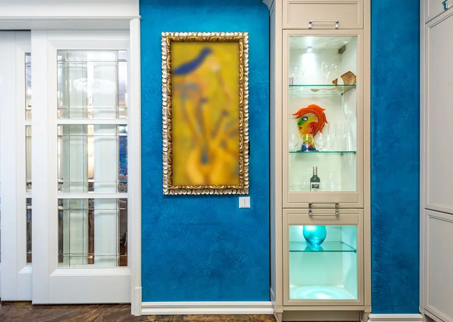 A teal alcove with gilt-framed pictures hung against it