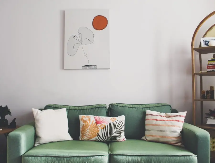 A sage green sofa under a single framed print