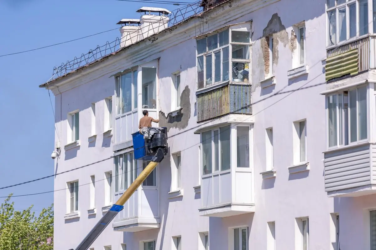 A painter on a cherry picker working across an apartment facade