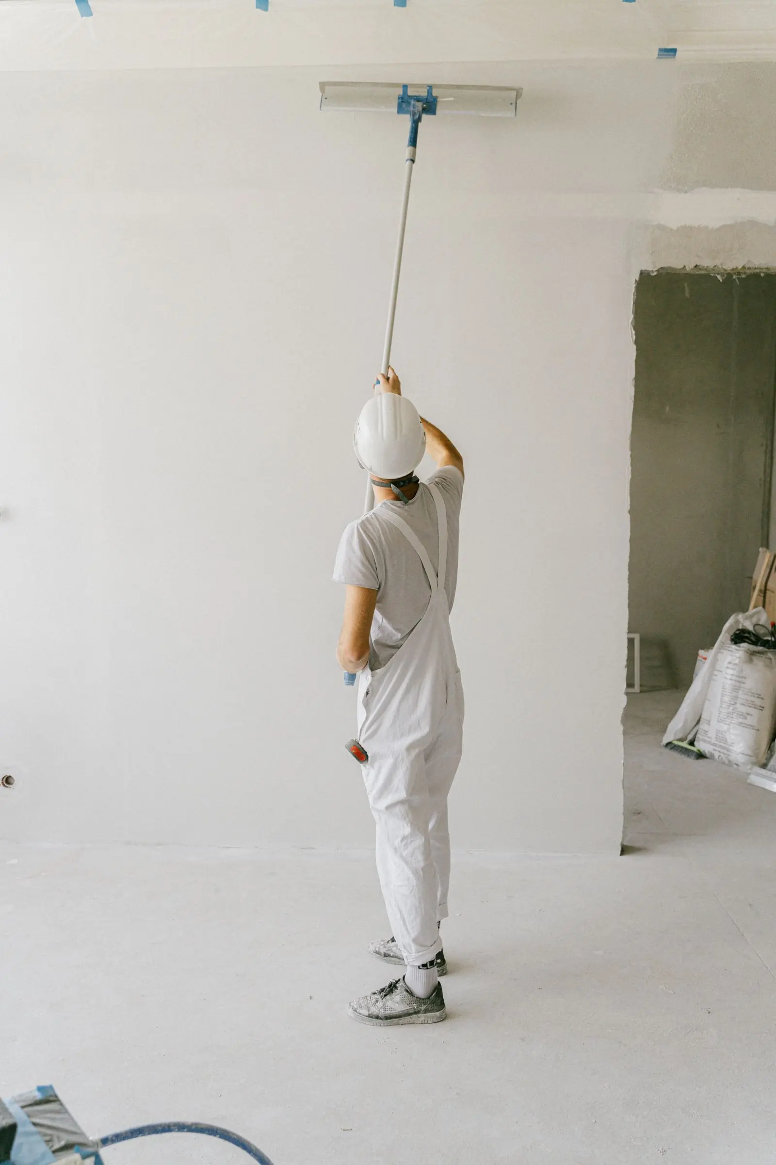 A decorator rolling out a freshly sealed ceiling