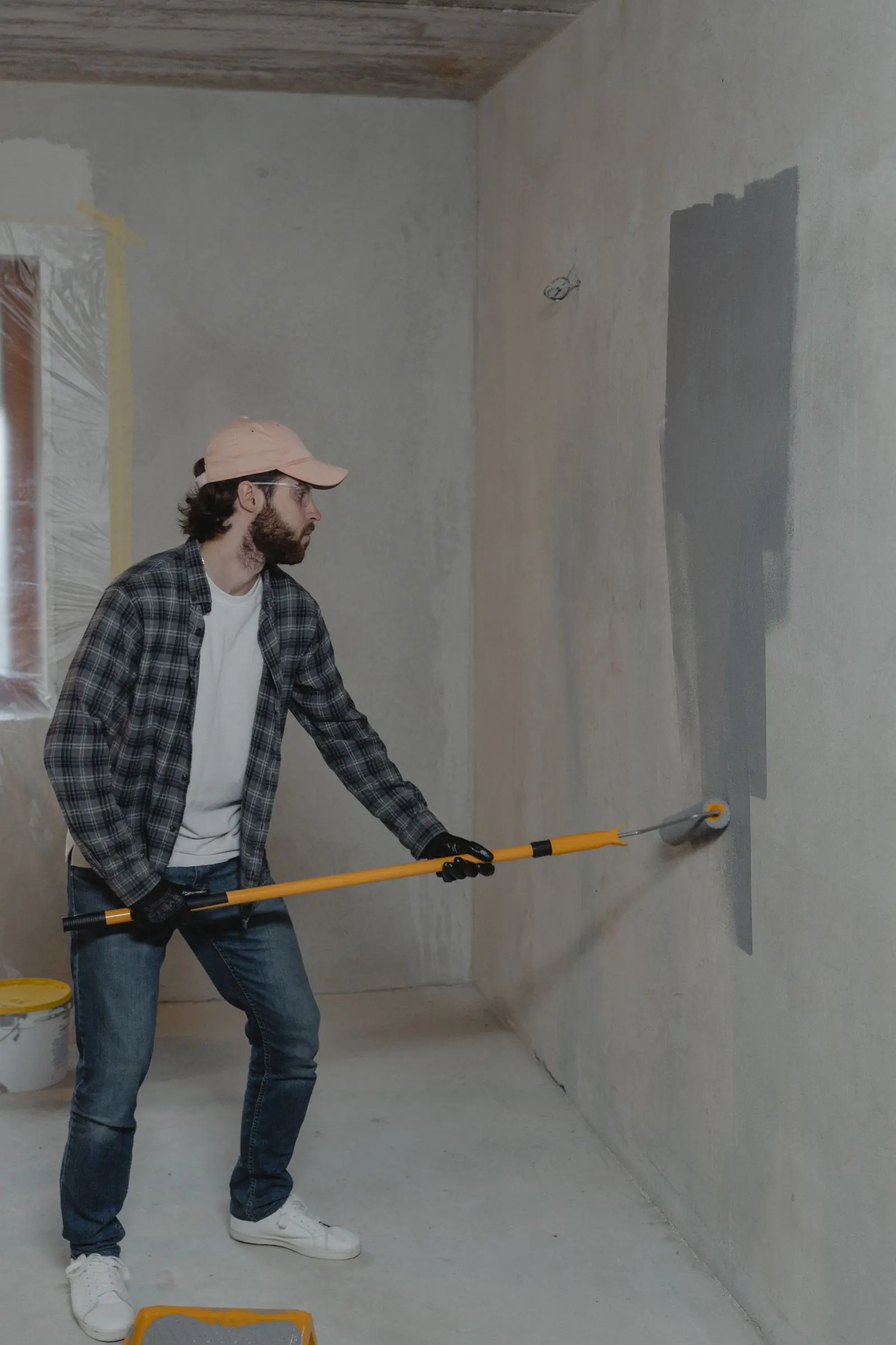 A decorator working a long-reach roller across a primed wall