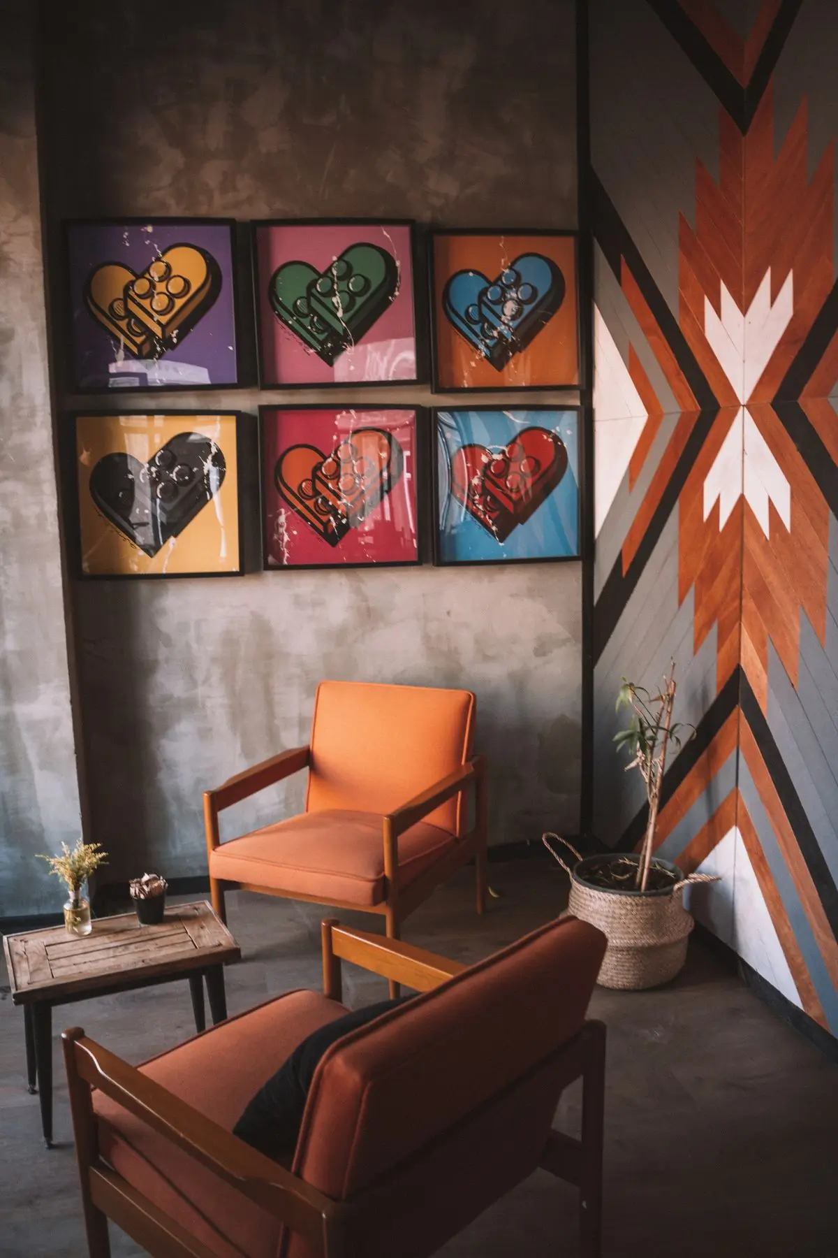 An orange armchair against a wall of framed pieces and a painted panel