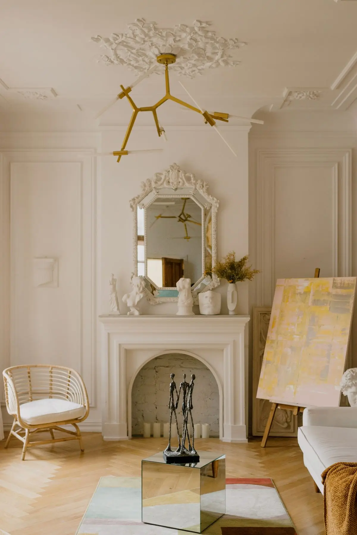 A pale drawing room with an ornate mirror over a fireplace