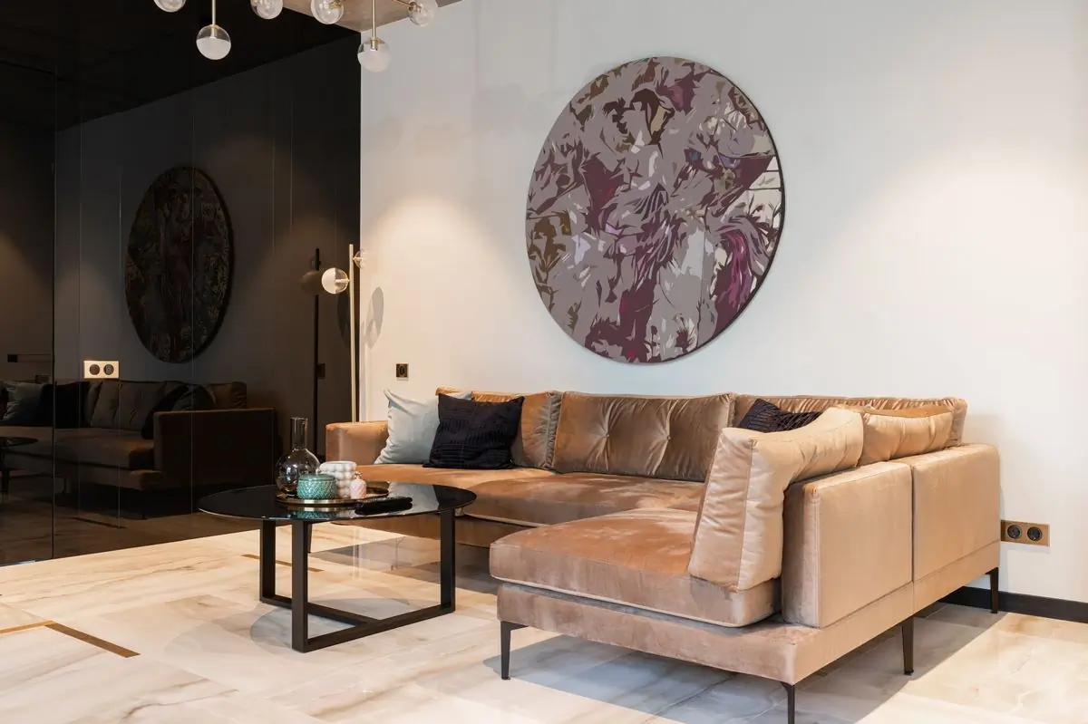 A finished sitting room in warm neutrals with a circular artwork above the sofa