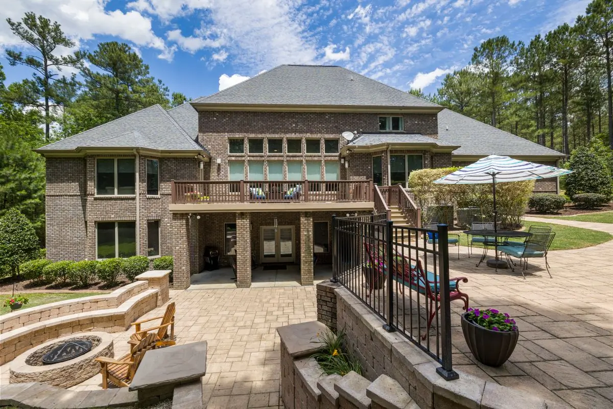 A brick house with a stone terrace, fire pit and kept lawns around it
