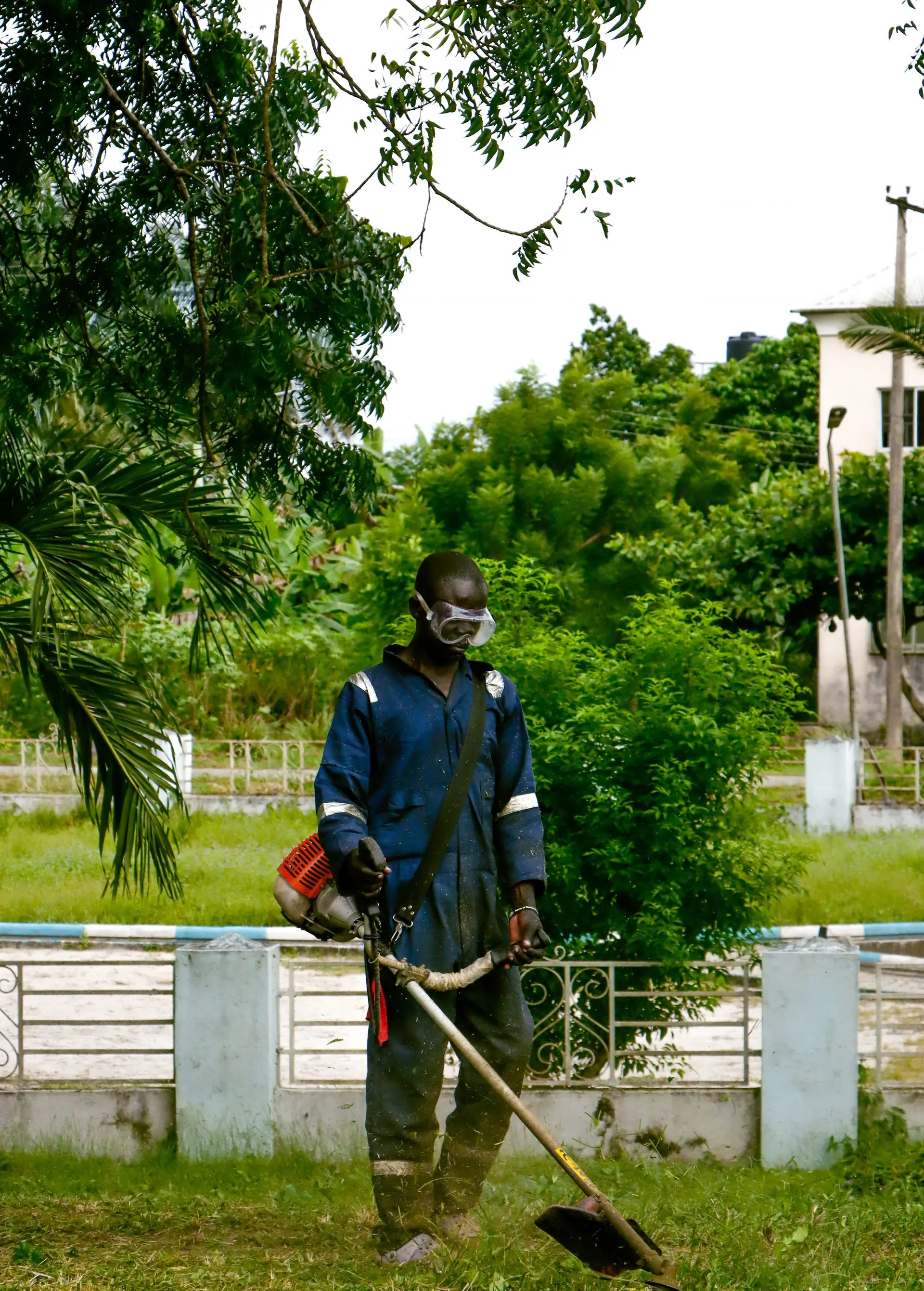 A Grove gardener edging a lawn under the trees at Airport Residential