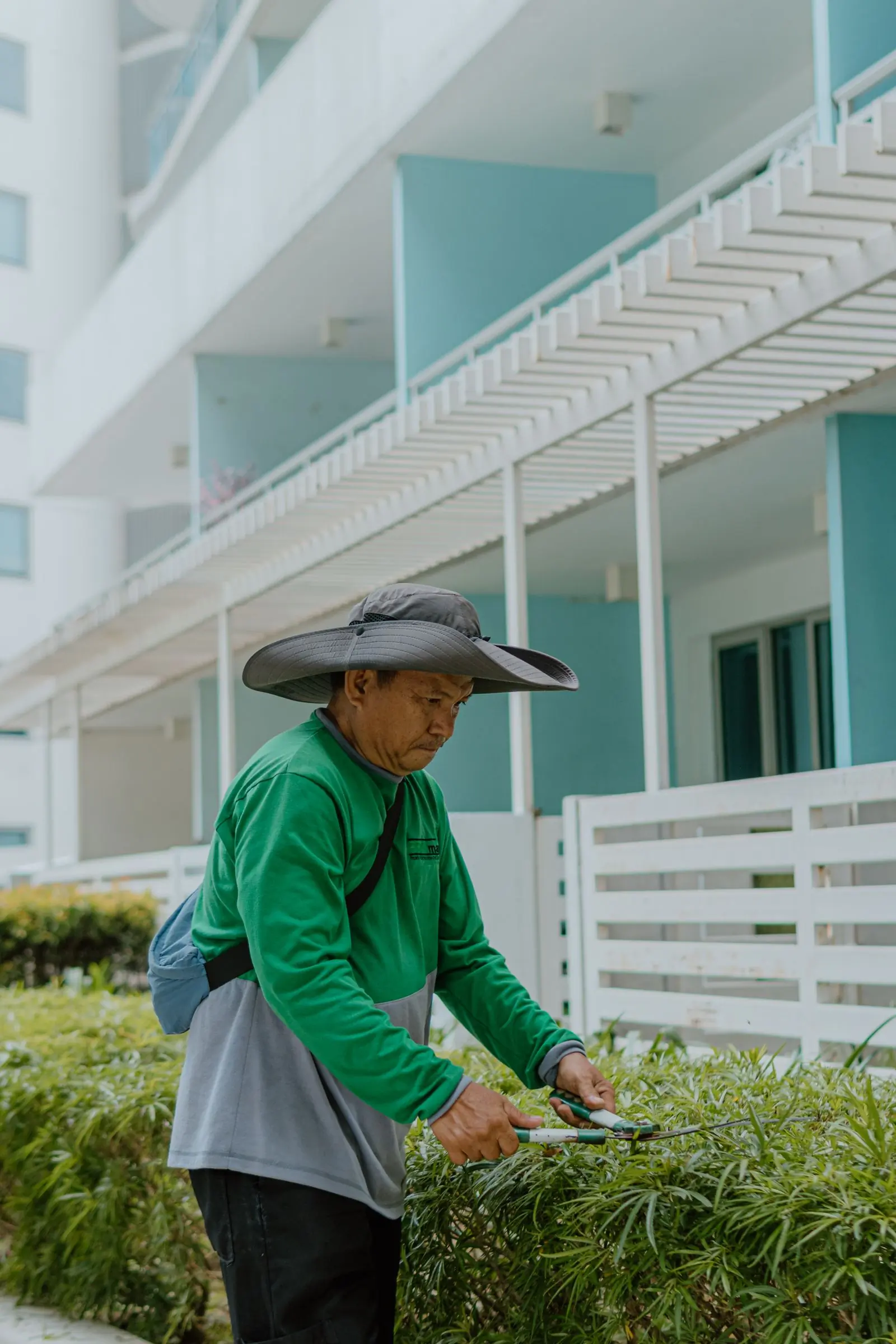A Grove gardener in a wide-brimmed hat working the beds outside a client's office