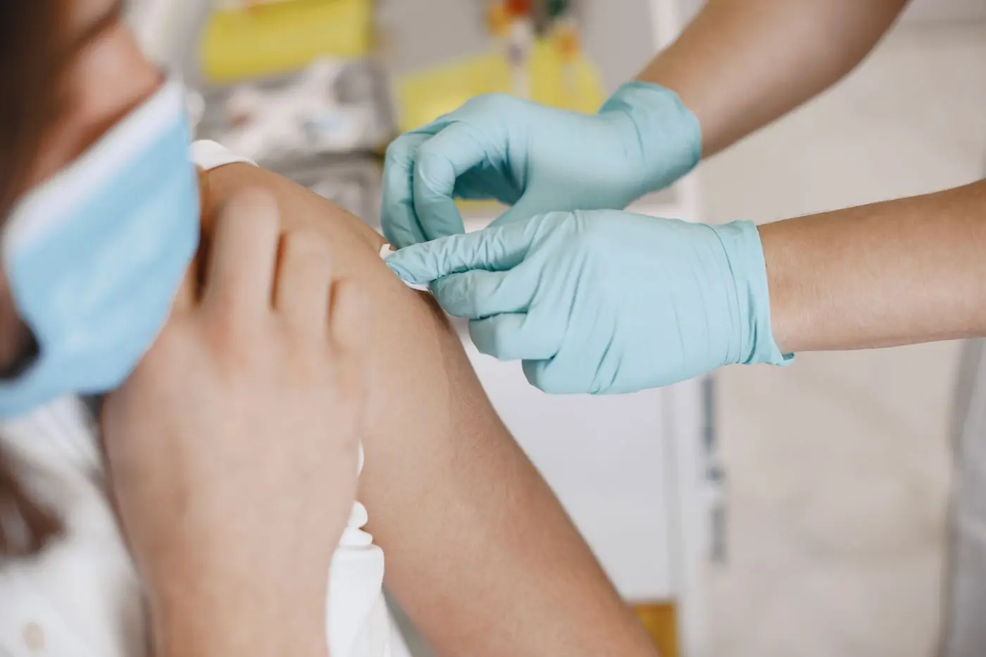 A nurse putting a dressing on a patient's arm after a vaccination
