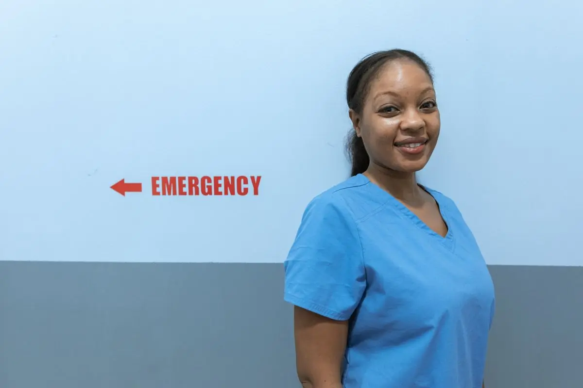 A nurse standing beside the clinic's emergency sign