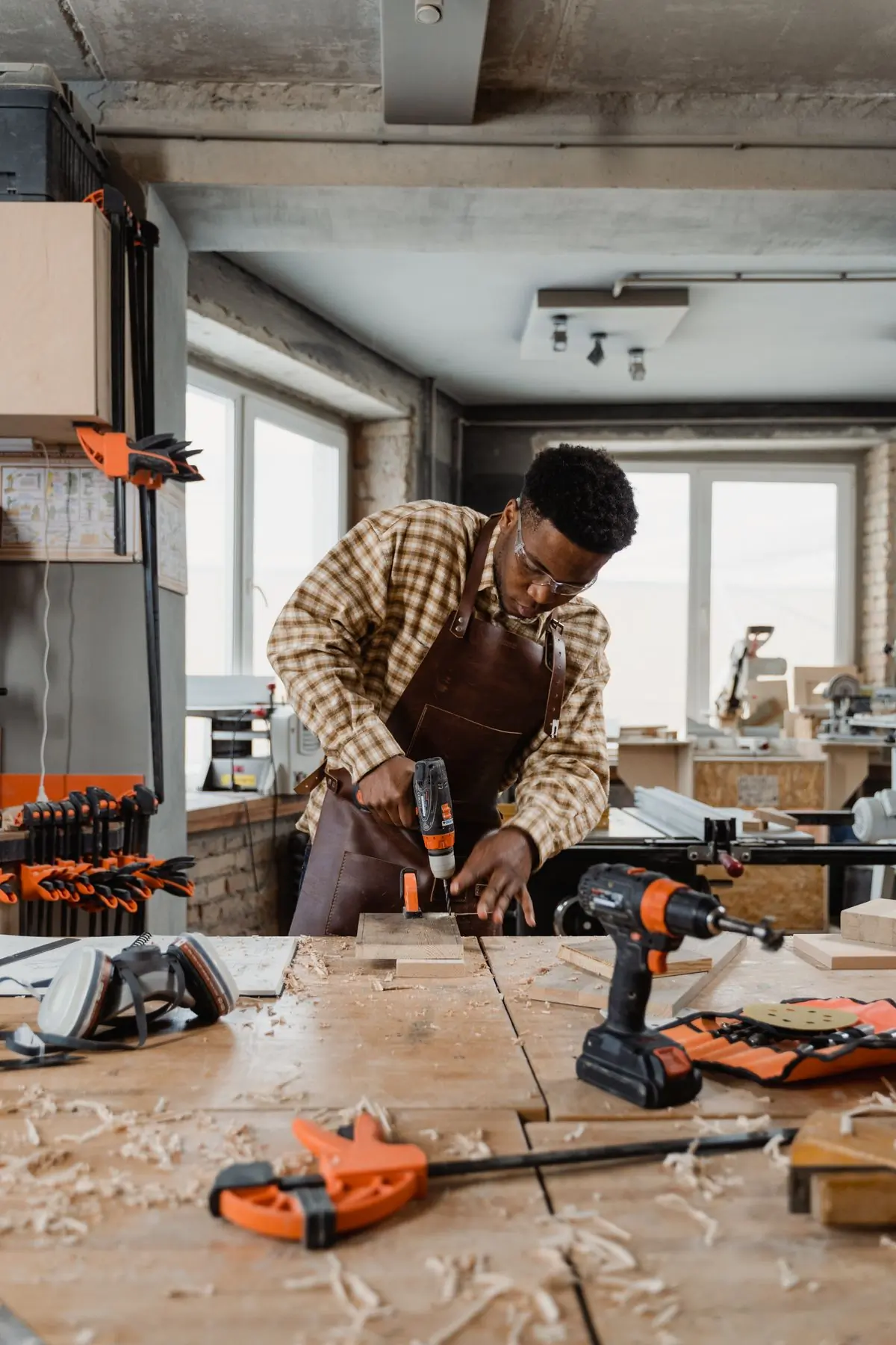 A Handy joiner drilling a shelf panel at the workshop bench