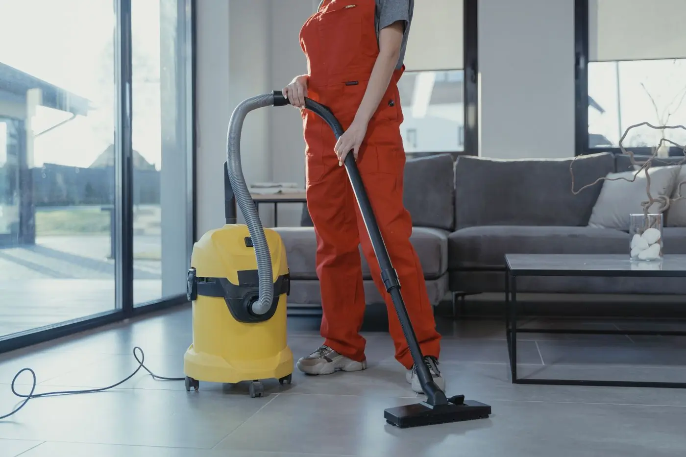 A Handy cleaner running an industrial vacuum across a living-room floor