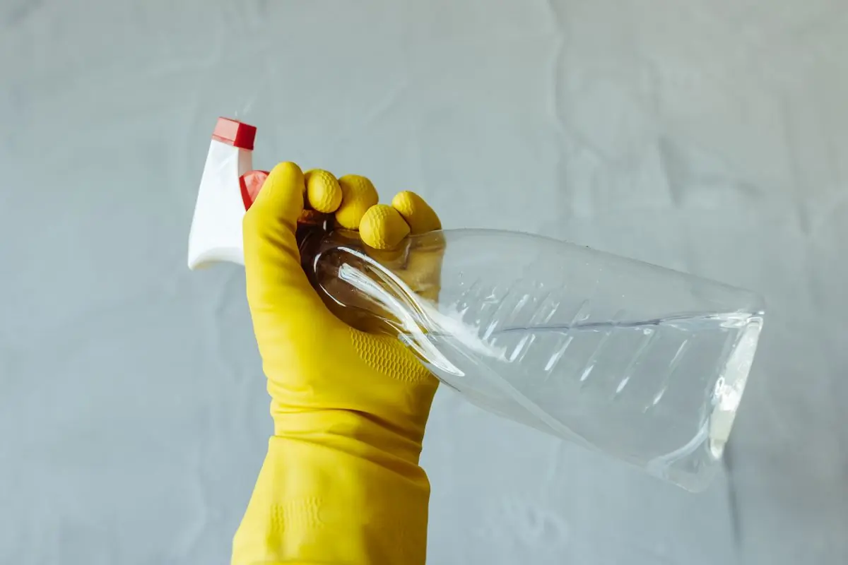 A gloved hand holding a spray bottle