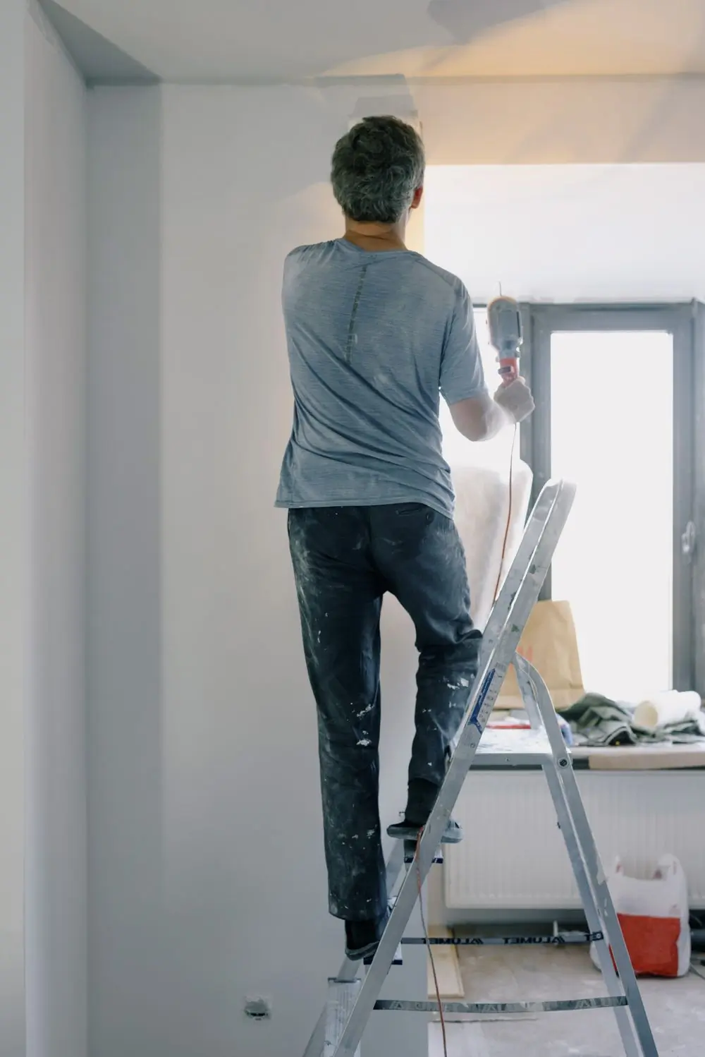 A Handy tradesman on a step ladder finishing a repair in an apartment
