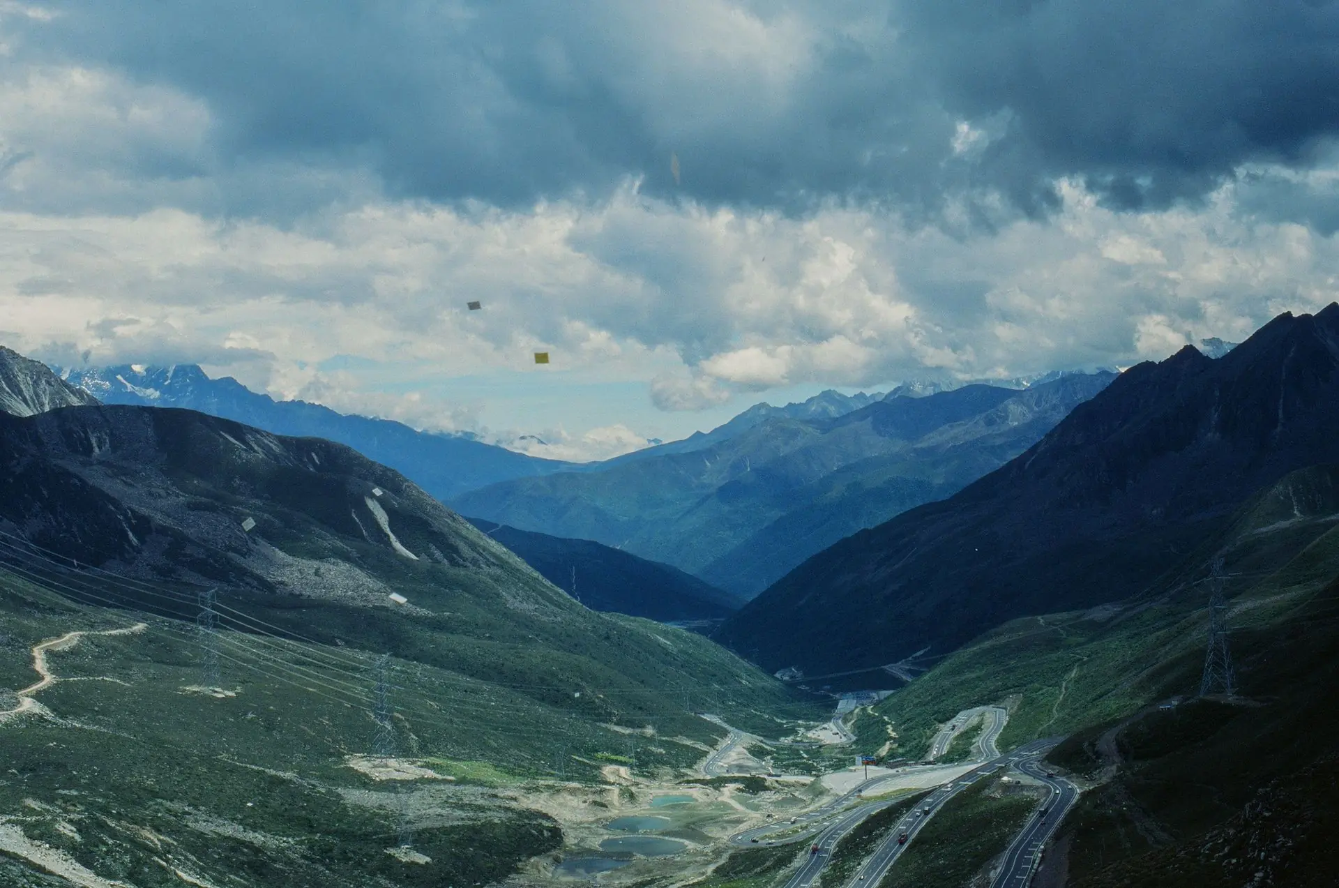 A mountain valley under dramatic cloud, with a road running through it