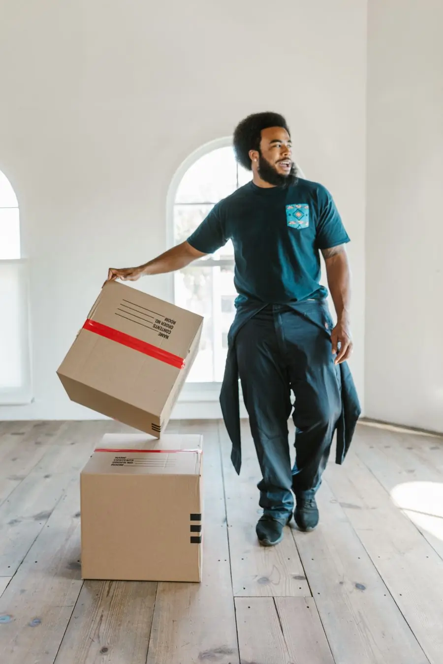 A mover handling a stack of labelled cartons in an empty room