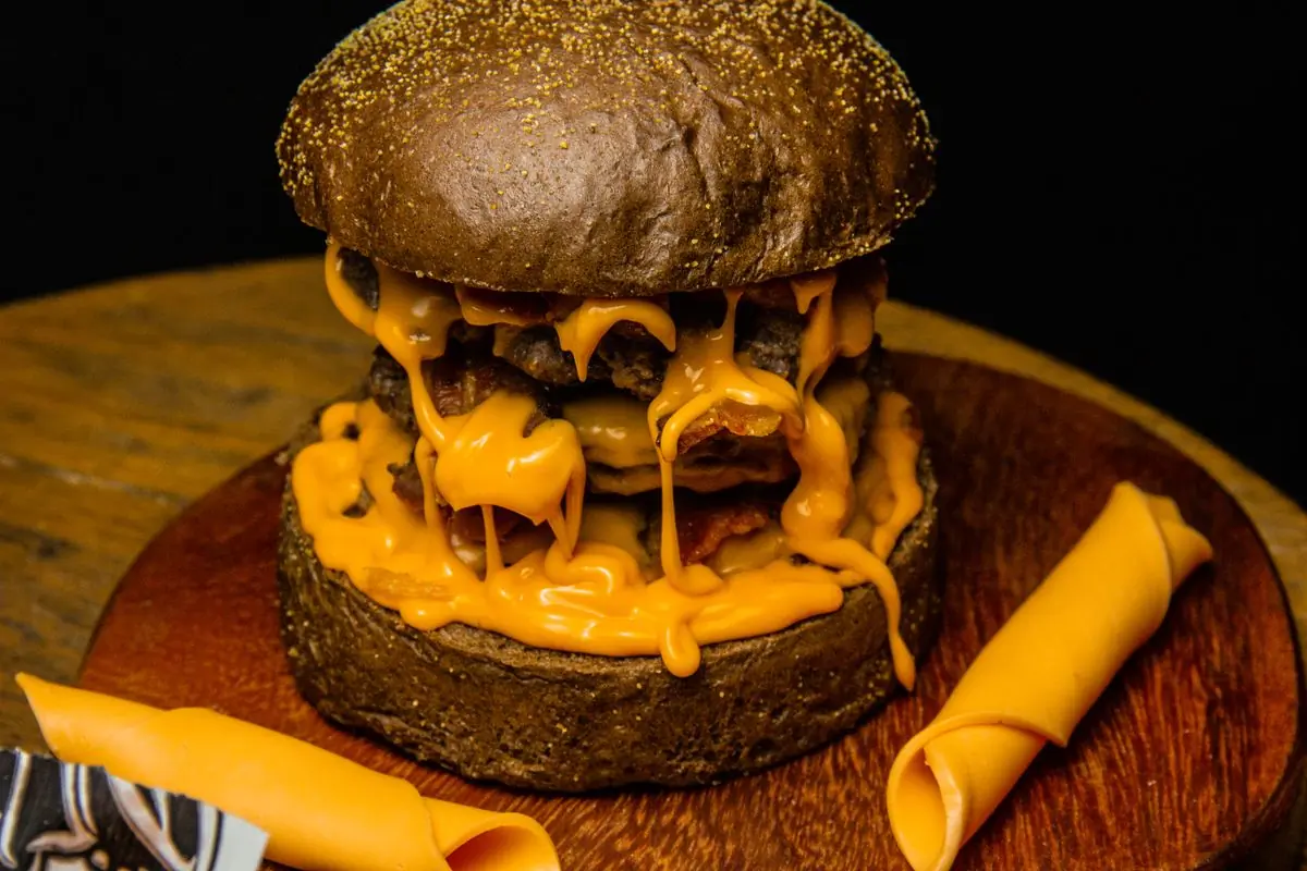 A truffle beef burger with melted cheese on a wooden board