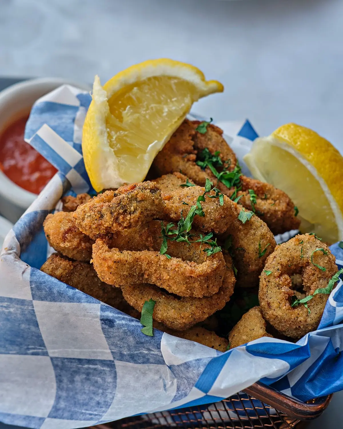 Crispy calamari served in a paper-lined box with lemon