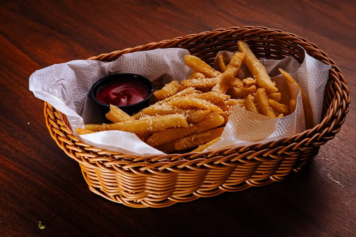 A basket of crisp golden fries with a pot of ketchup