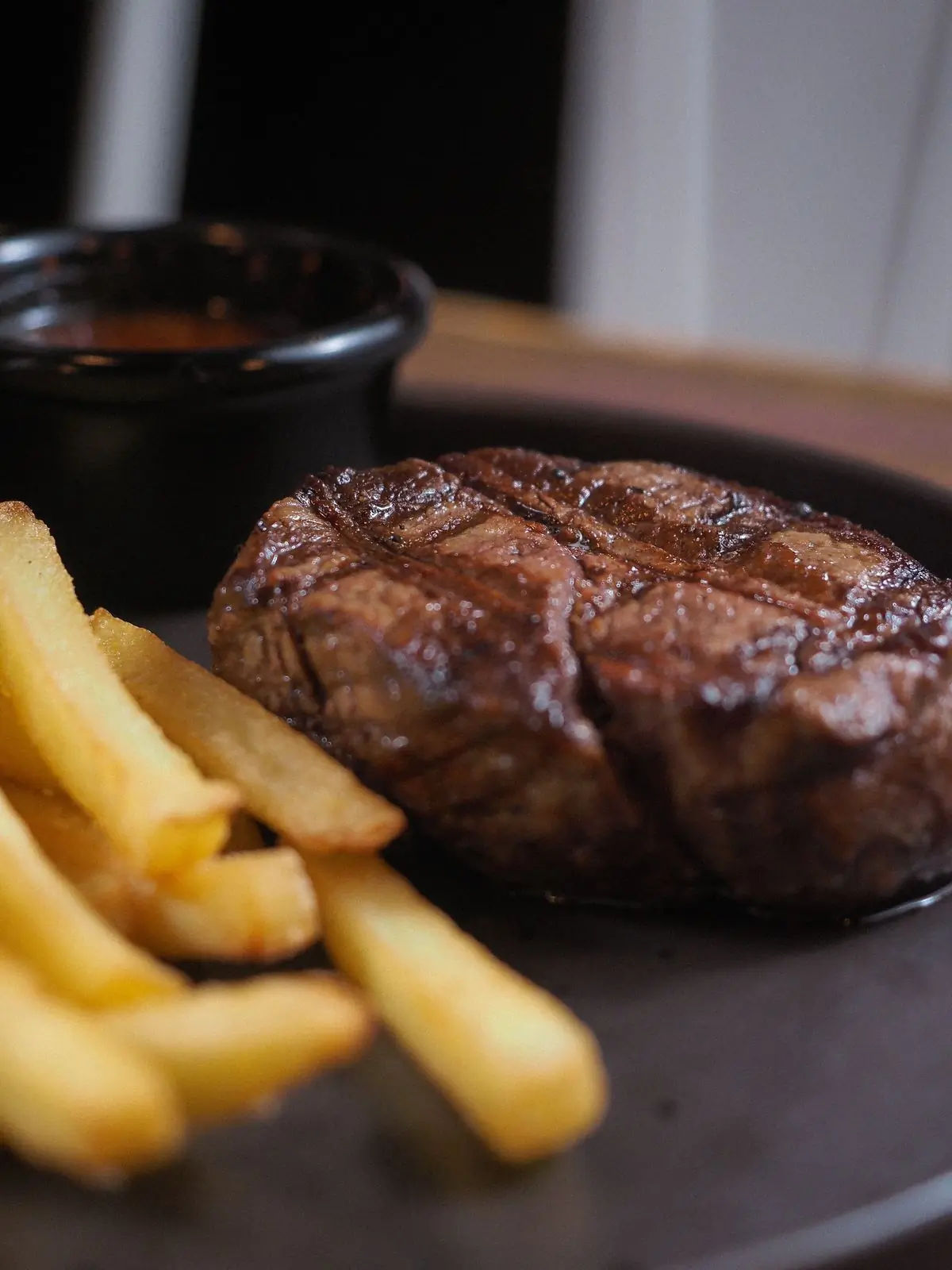 Sirloin steak and hand-cut fries on a dark plate