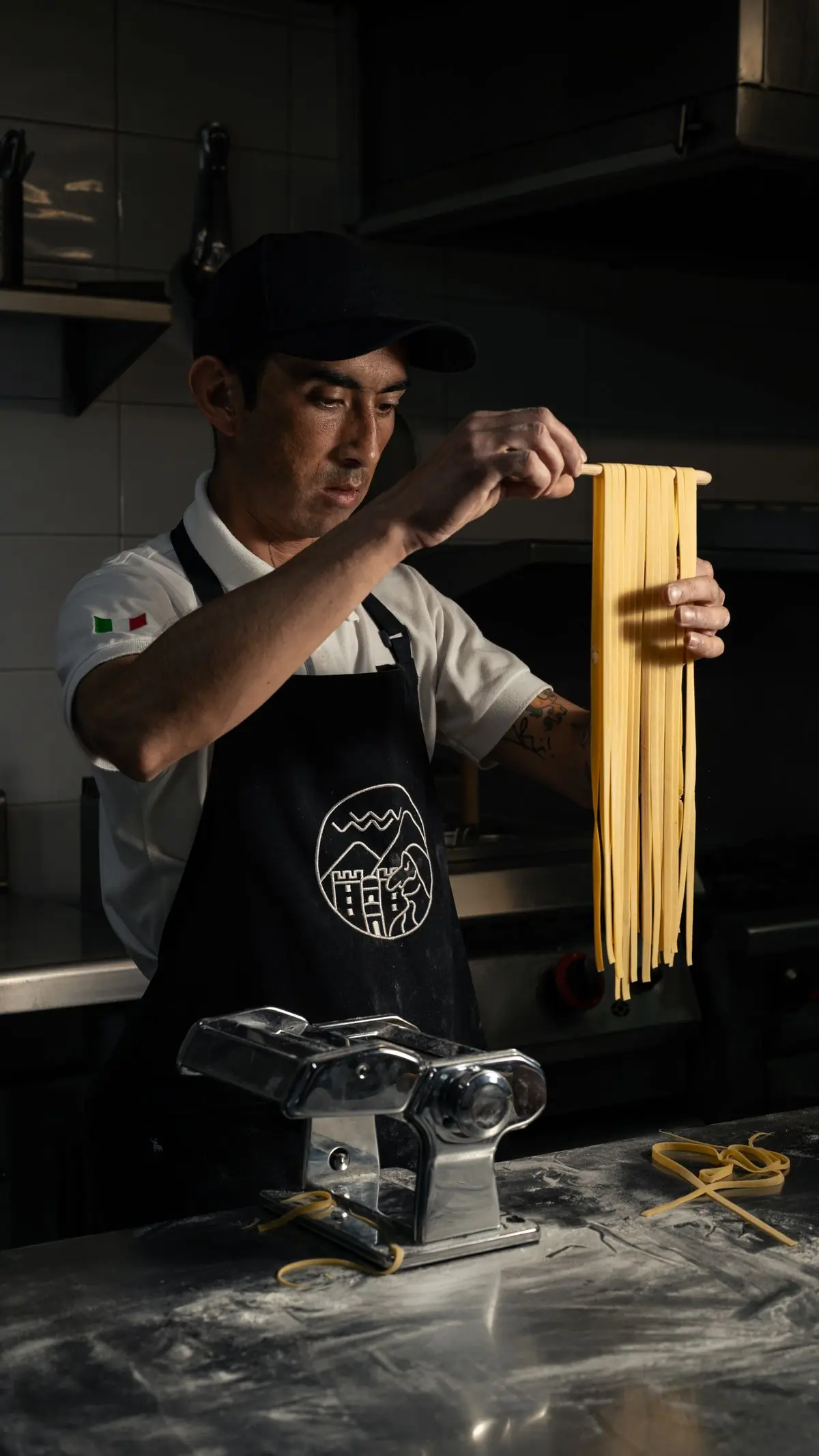 Fresh pasta going through a hand-cranked machine in the kitchen
