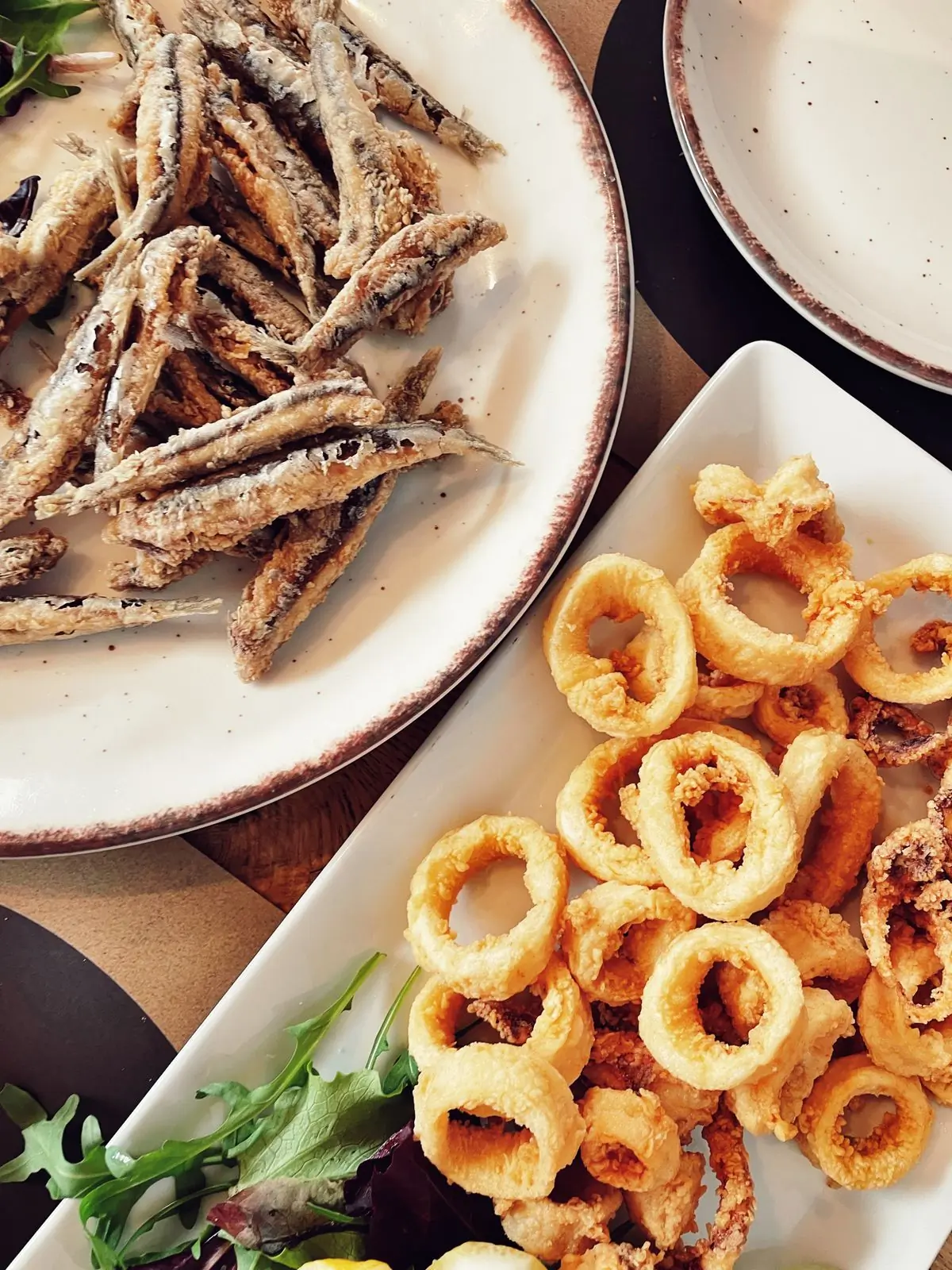 A platter of fried seafood served with fresh greens